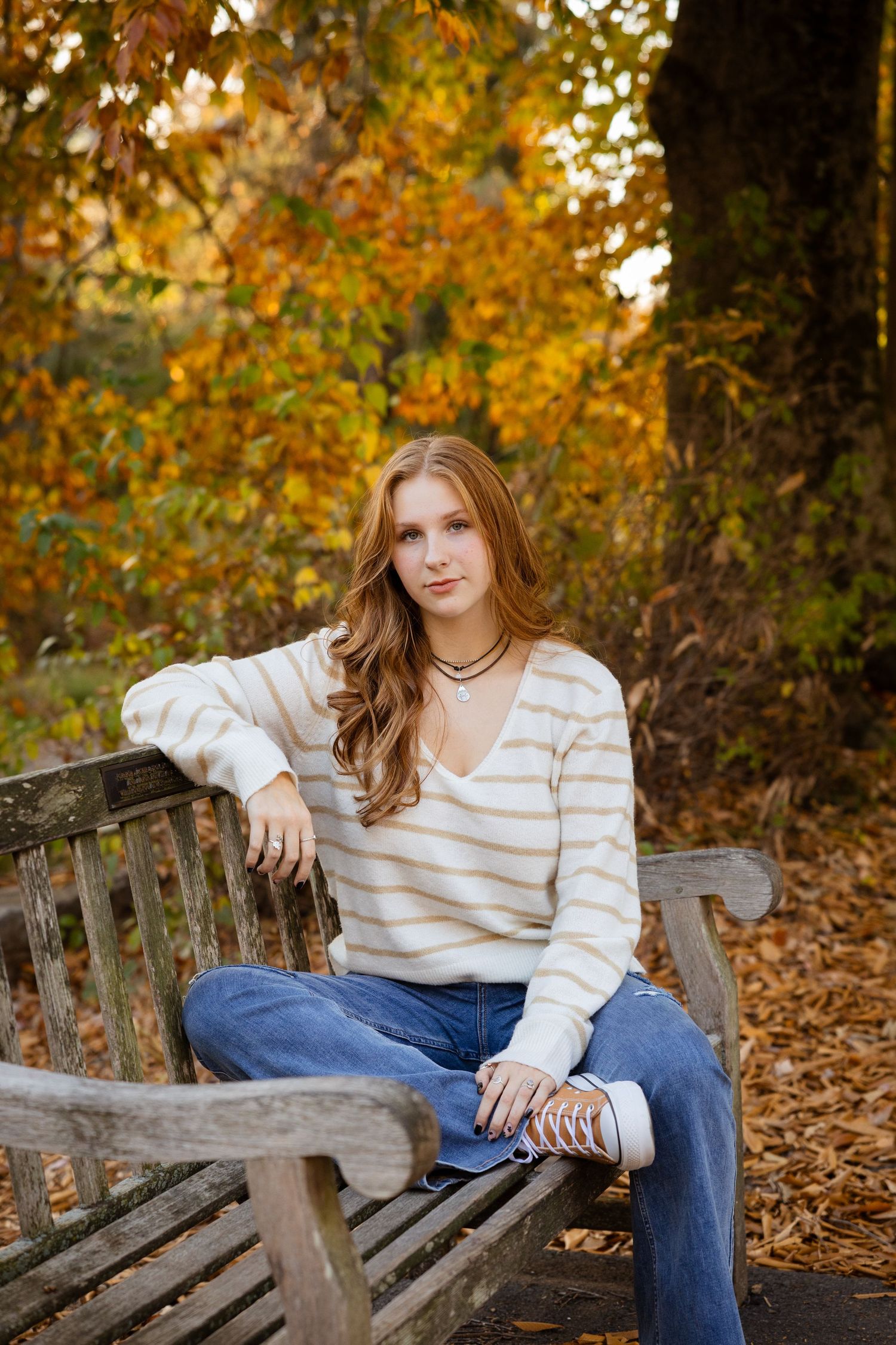 Casual outdoor portrait session on wooden bench during fall season.