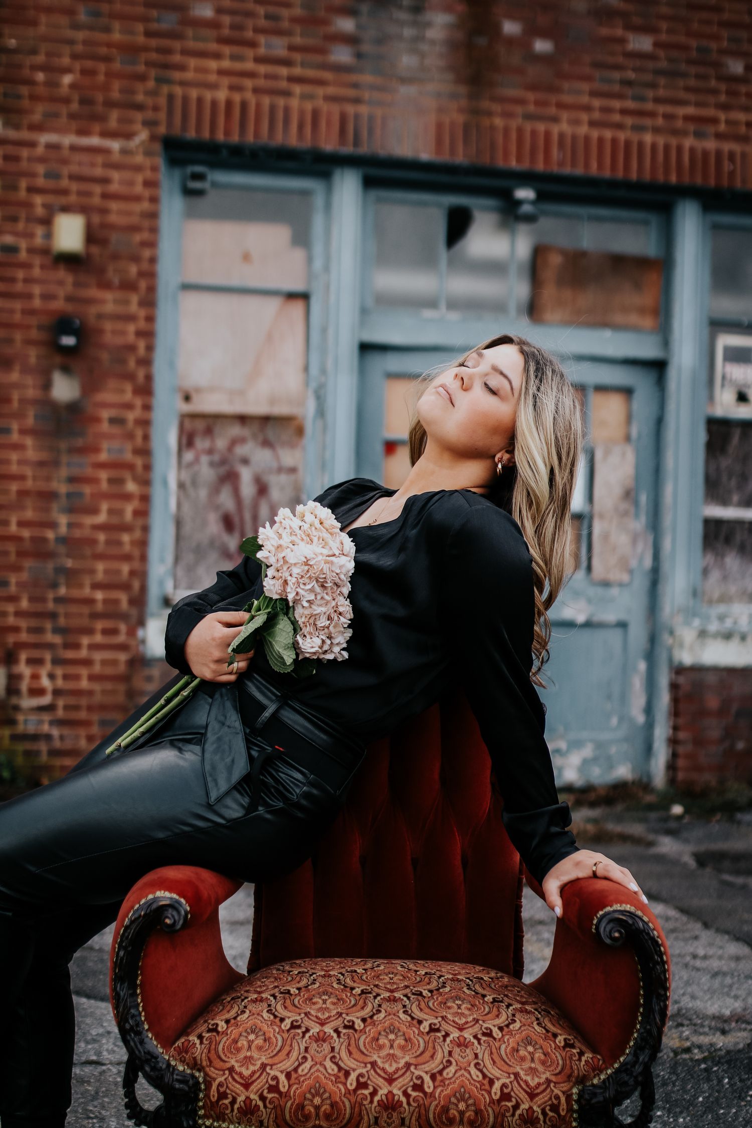 Dramatic fashion poses on a vintage red velvet chair with flowers.