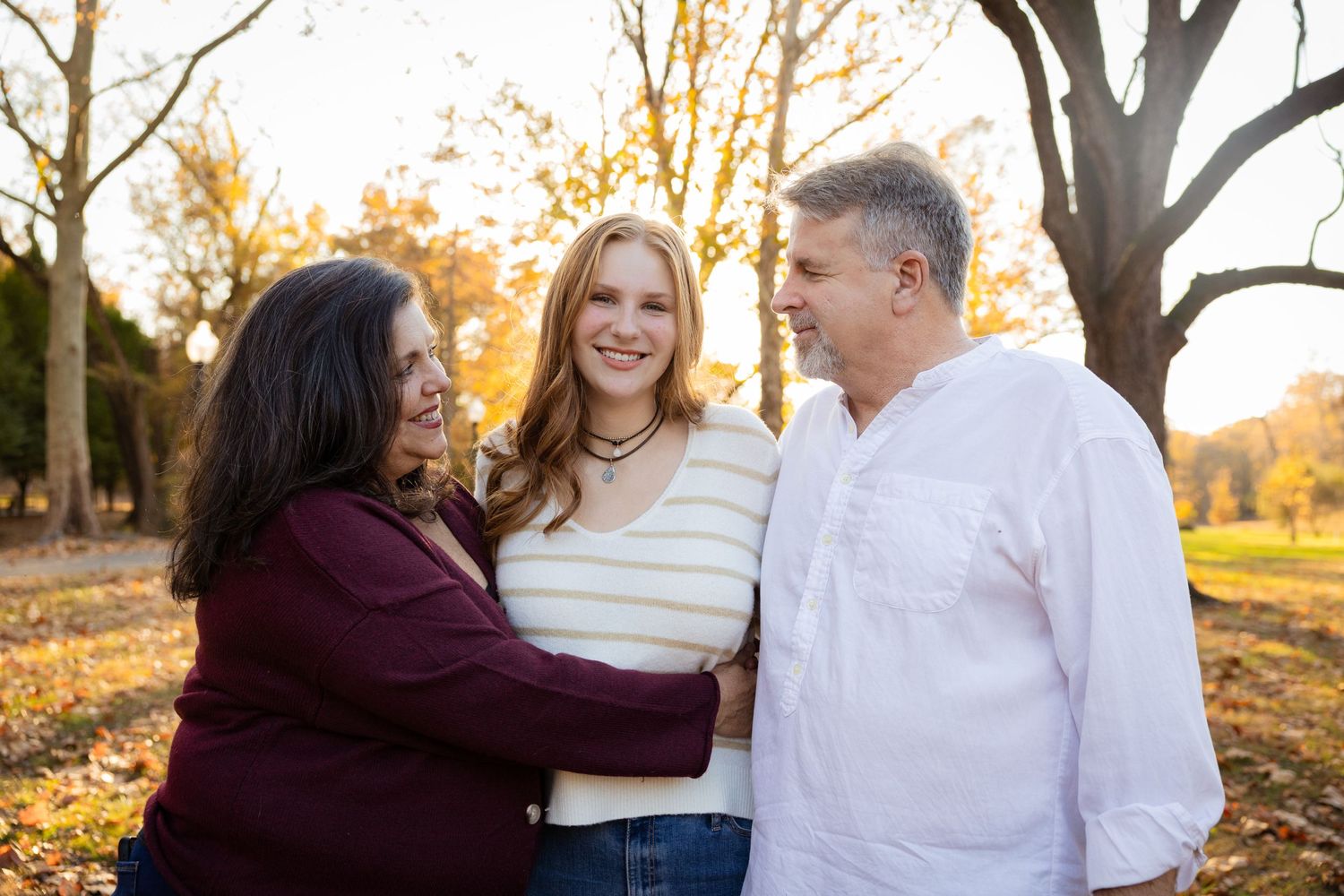 Family portrait session outdoors with warm autumn lighting and casual attire.