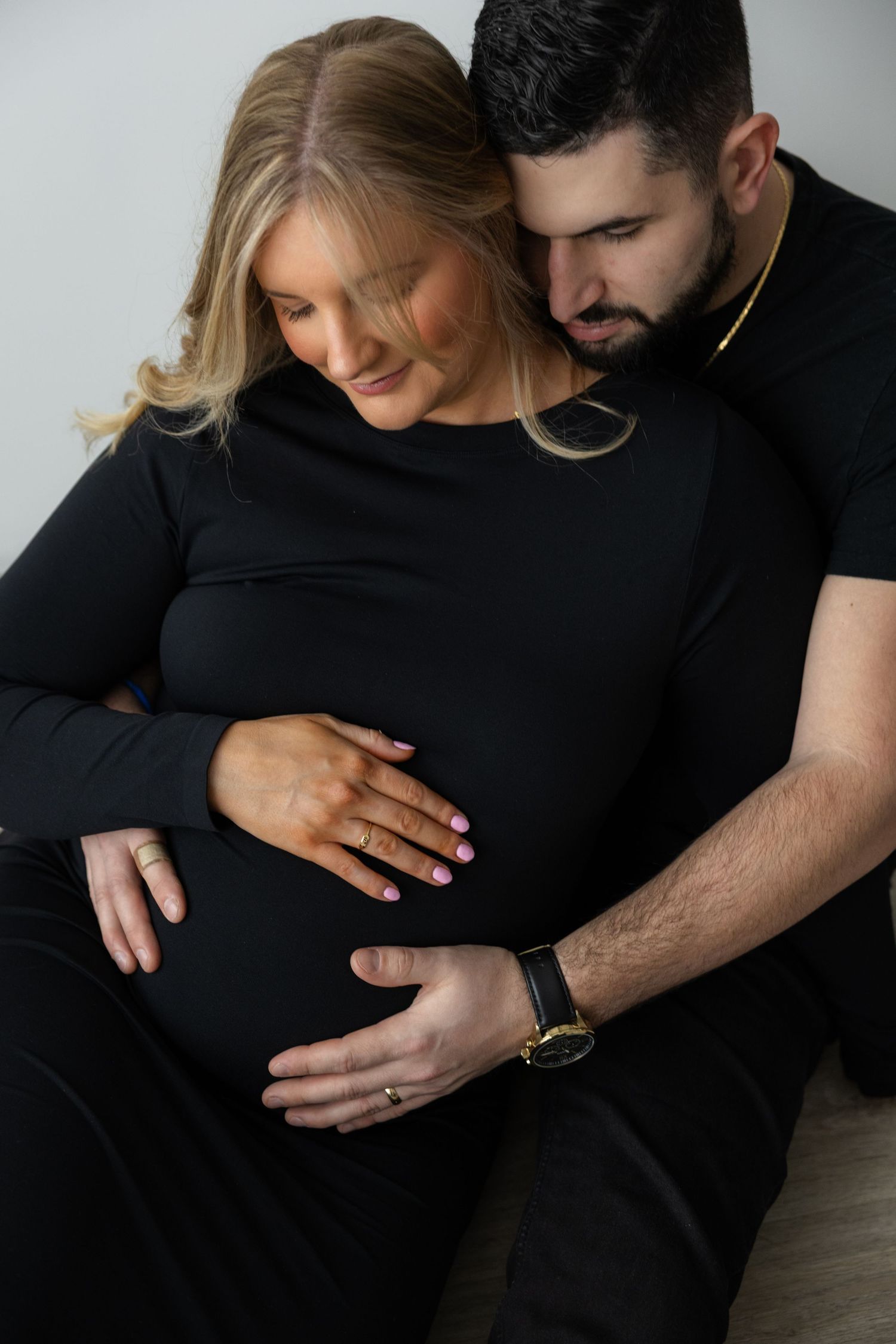 Artistic maternity portraits showing gentle embrace and baby bump in monochrome style.