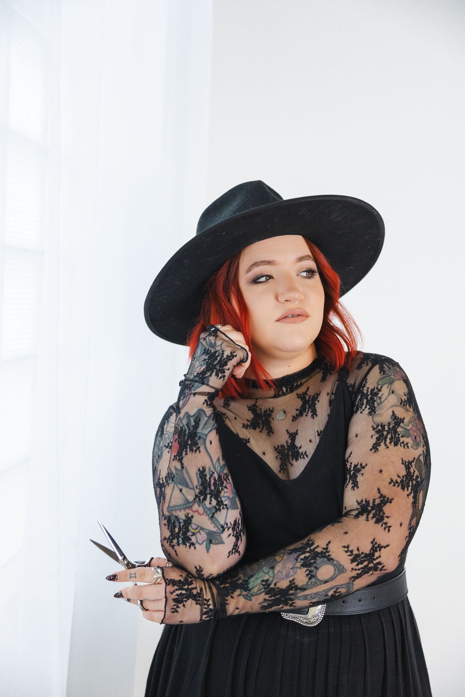 Fashion model in black dress and wide-brim hat showcases elegant gothic style.