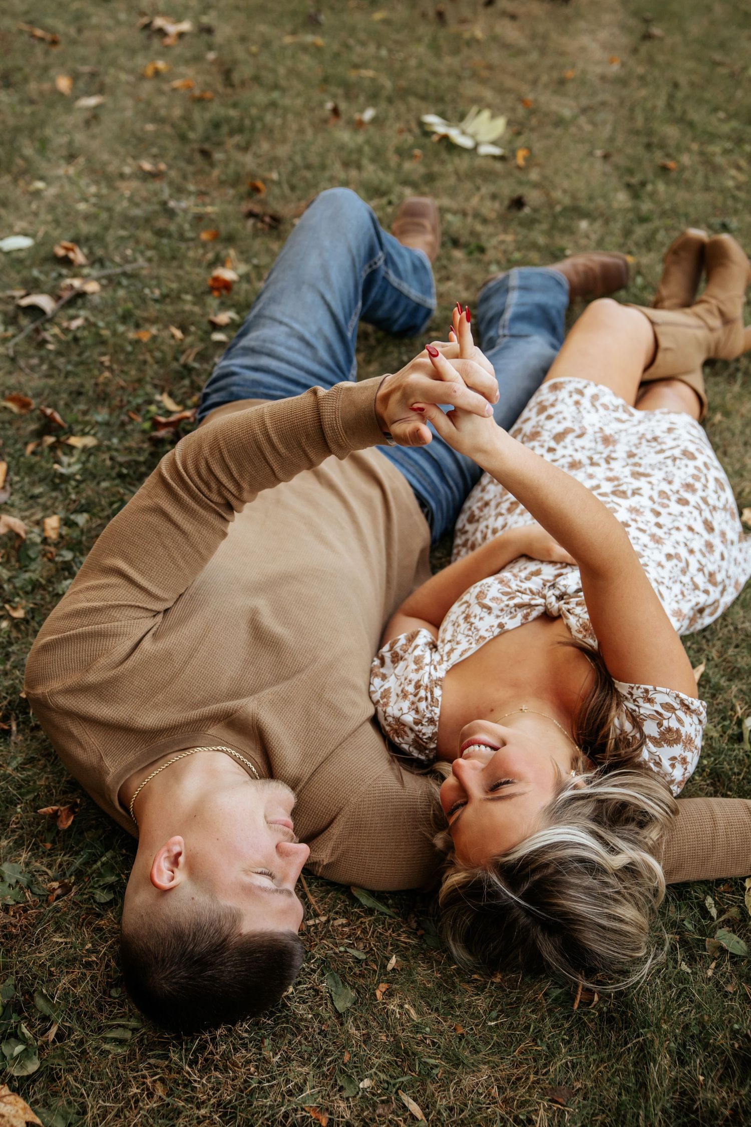 Intimate moment captured of couple lying on grass during fall photoshoot.