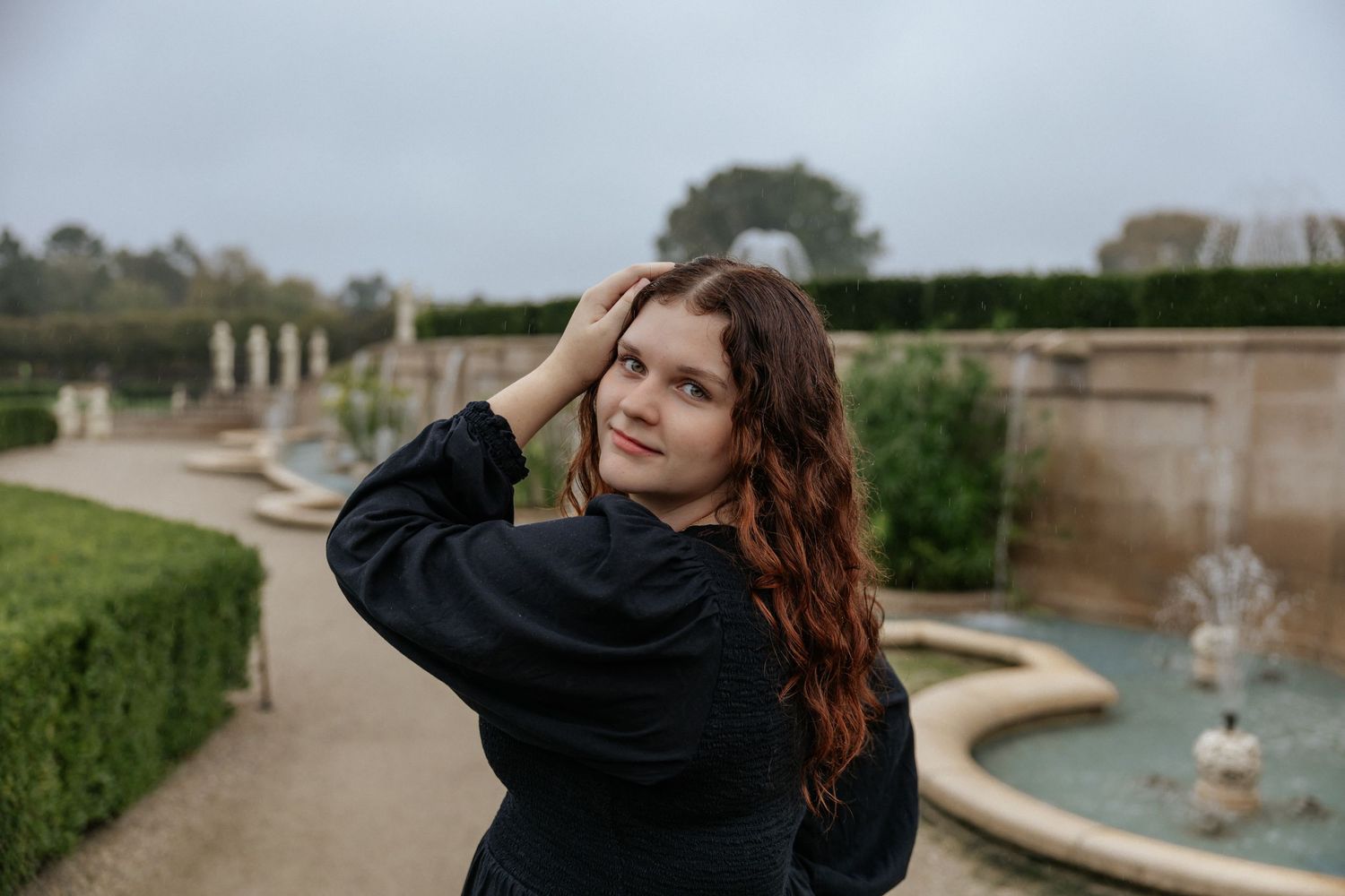 Artistic outdoor photoshoot with architectural elements and natural landscaping.