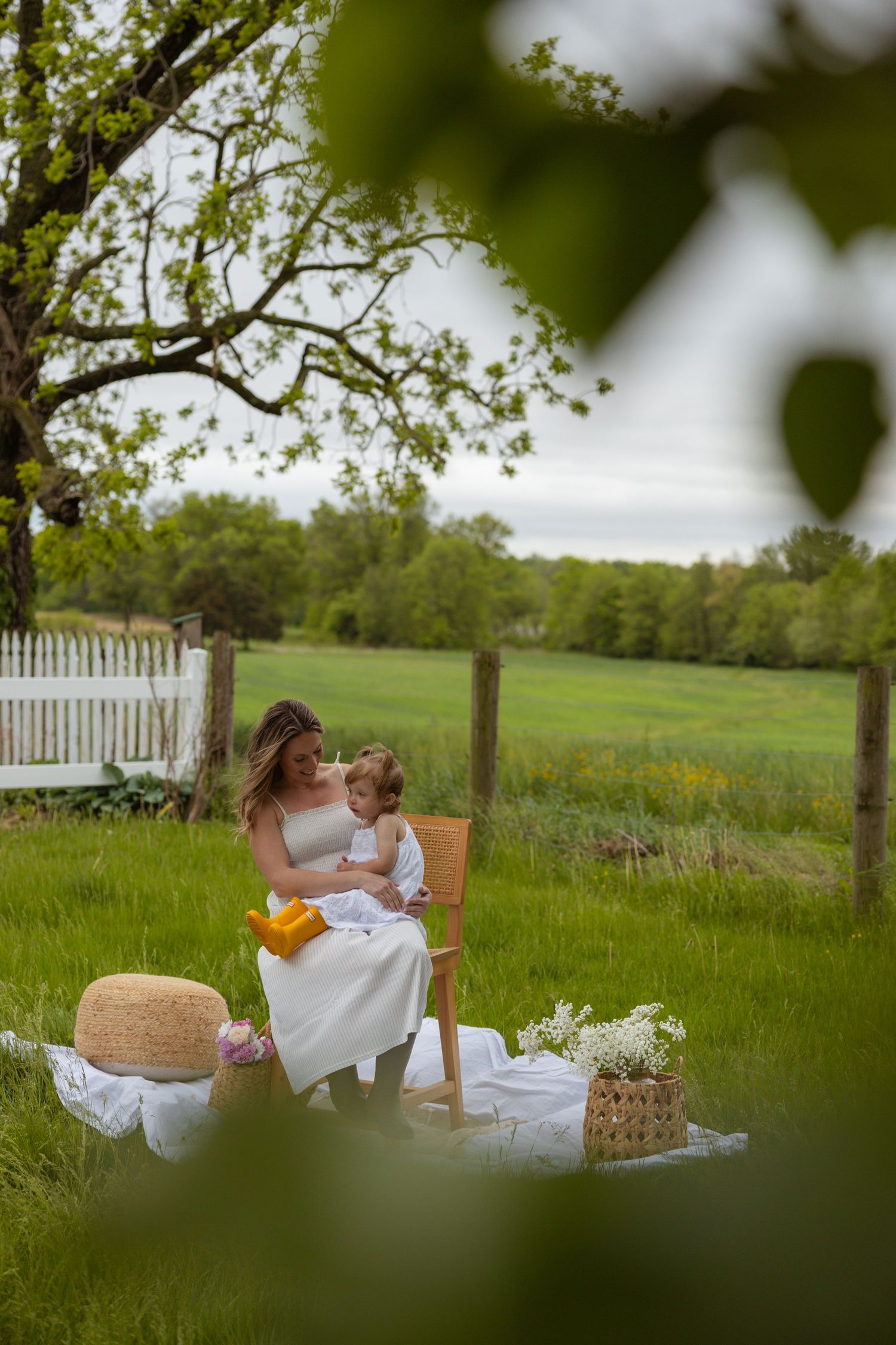A peaceful outdoor scene with a picnic blanket and basket framed by green foliage.