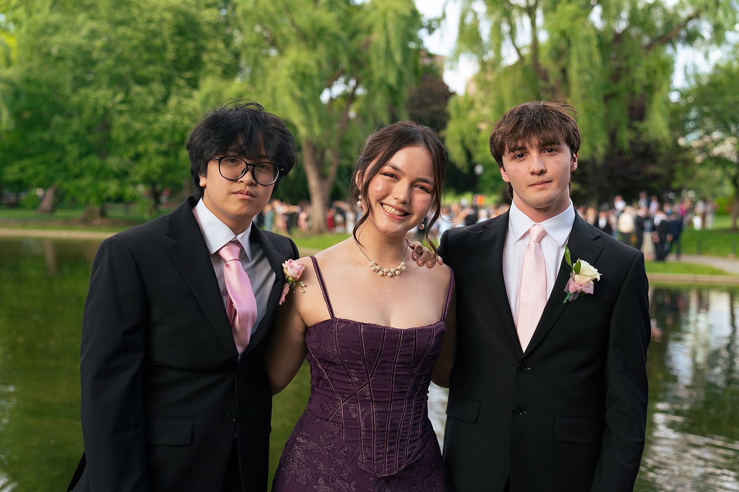 Two guys and a girl pose in front of the Swan Pond at Boston Public Garden.