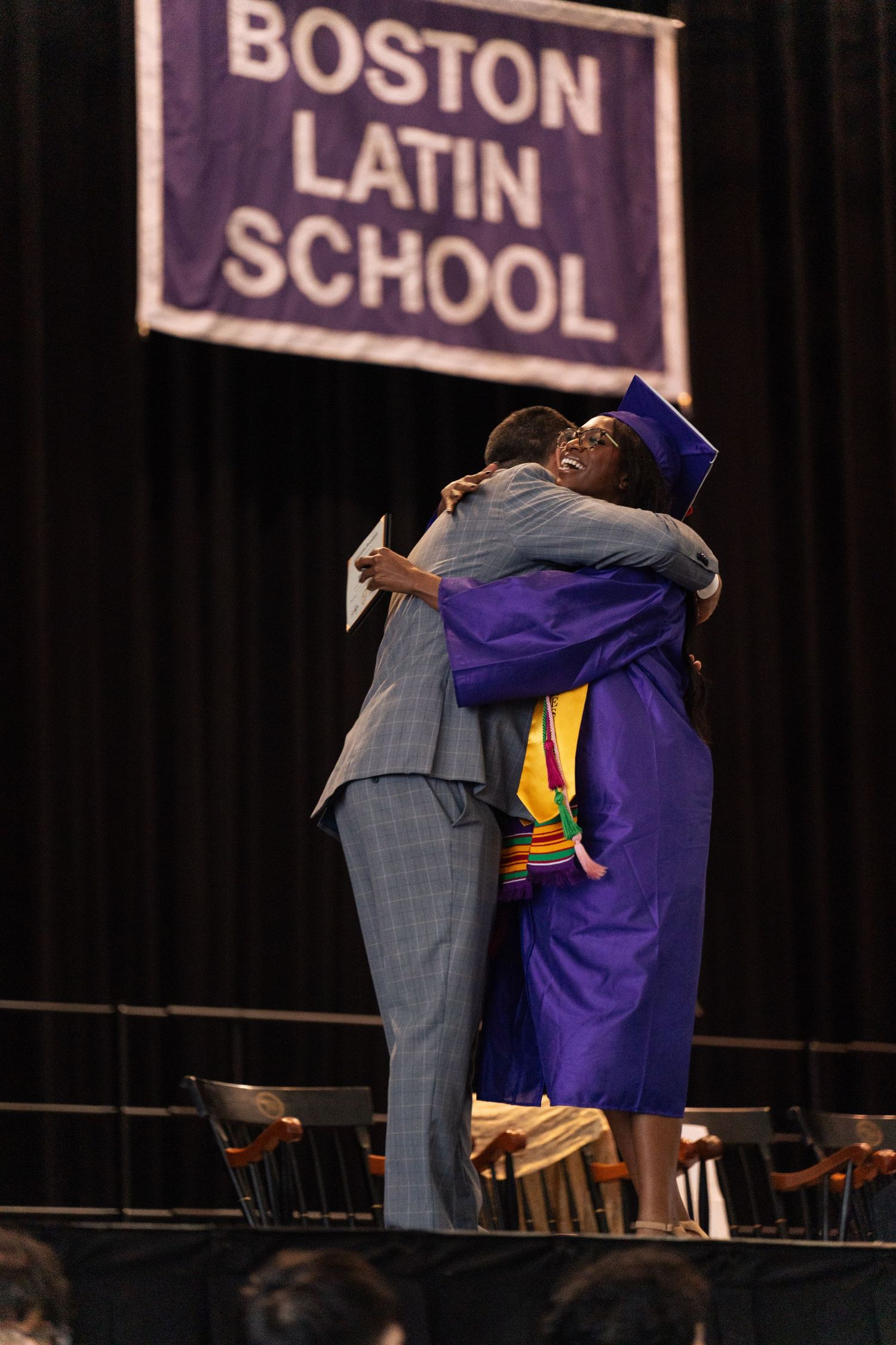 The graduate hugs their principal in a heartfelt moment.