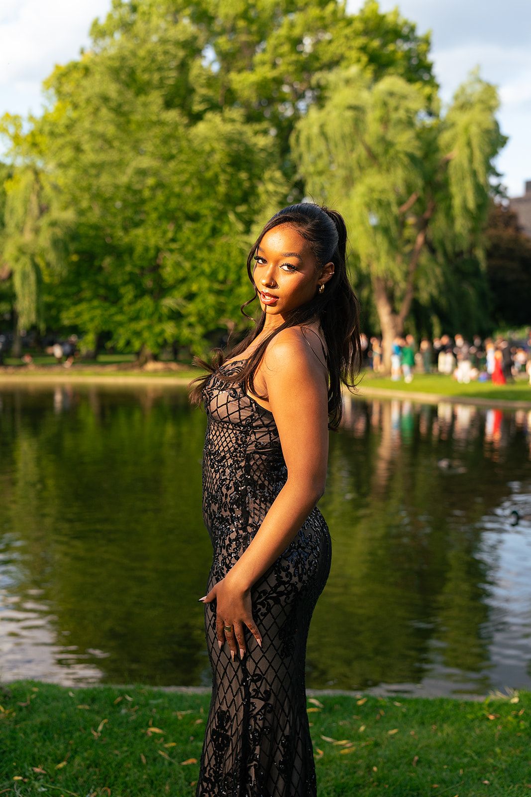 A girl poses in front of the Swan Pond at Boston Public Garden
