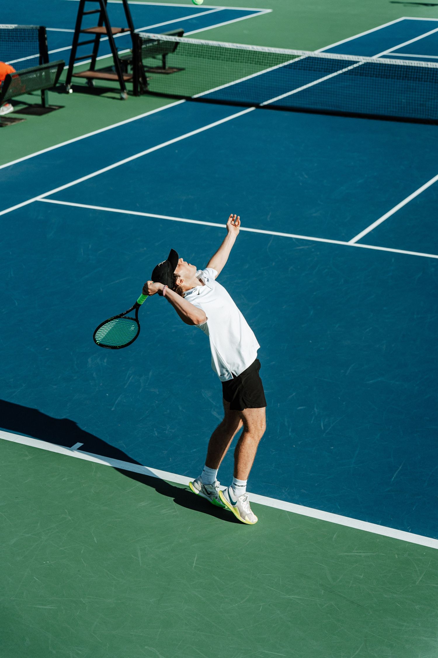 A tennis player jumps and reaches for a pass.