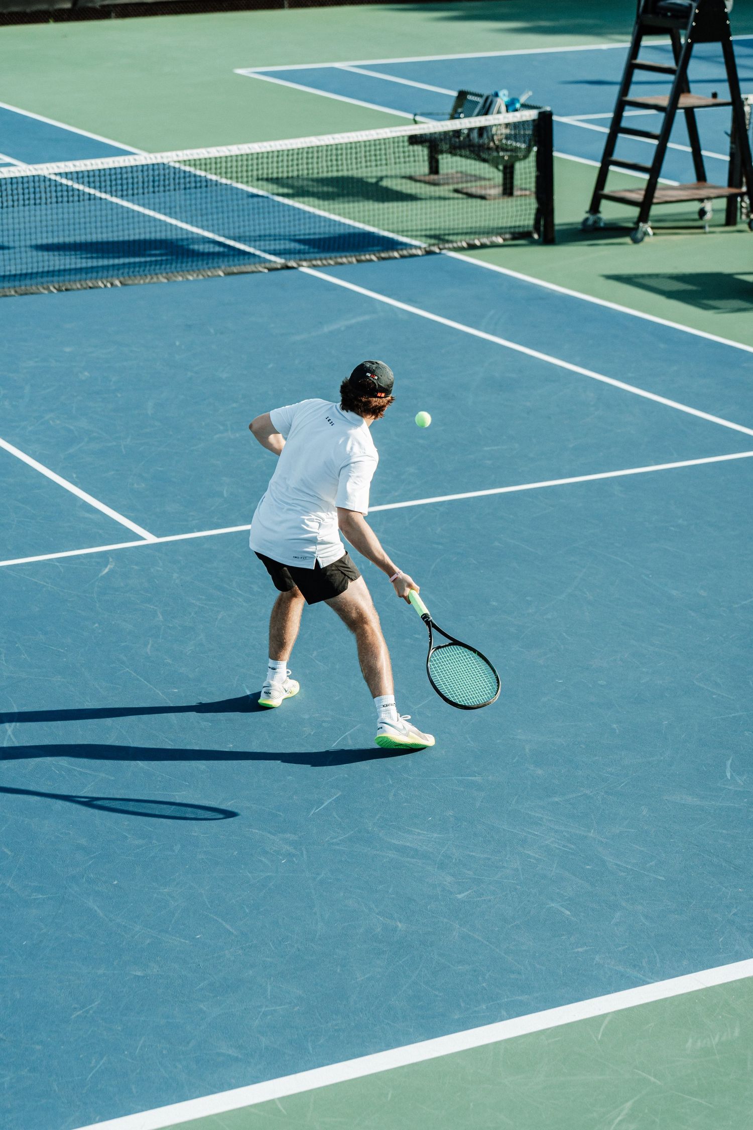 A tennis player returns a serve with an underhand hit.