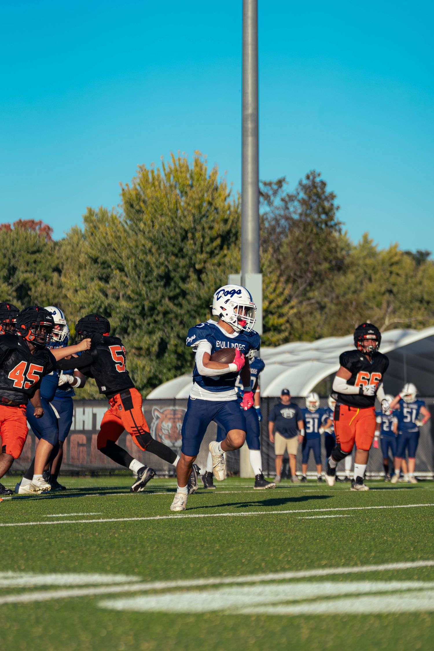 A football player runs the ball down the field.