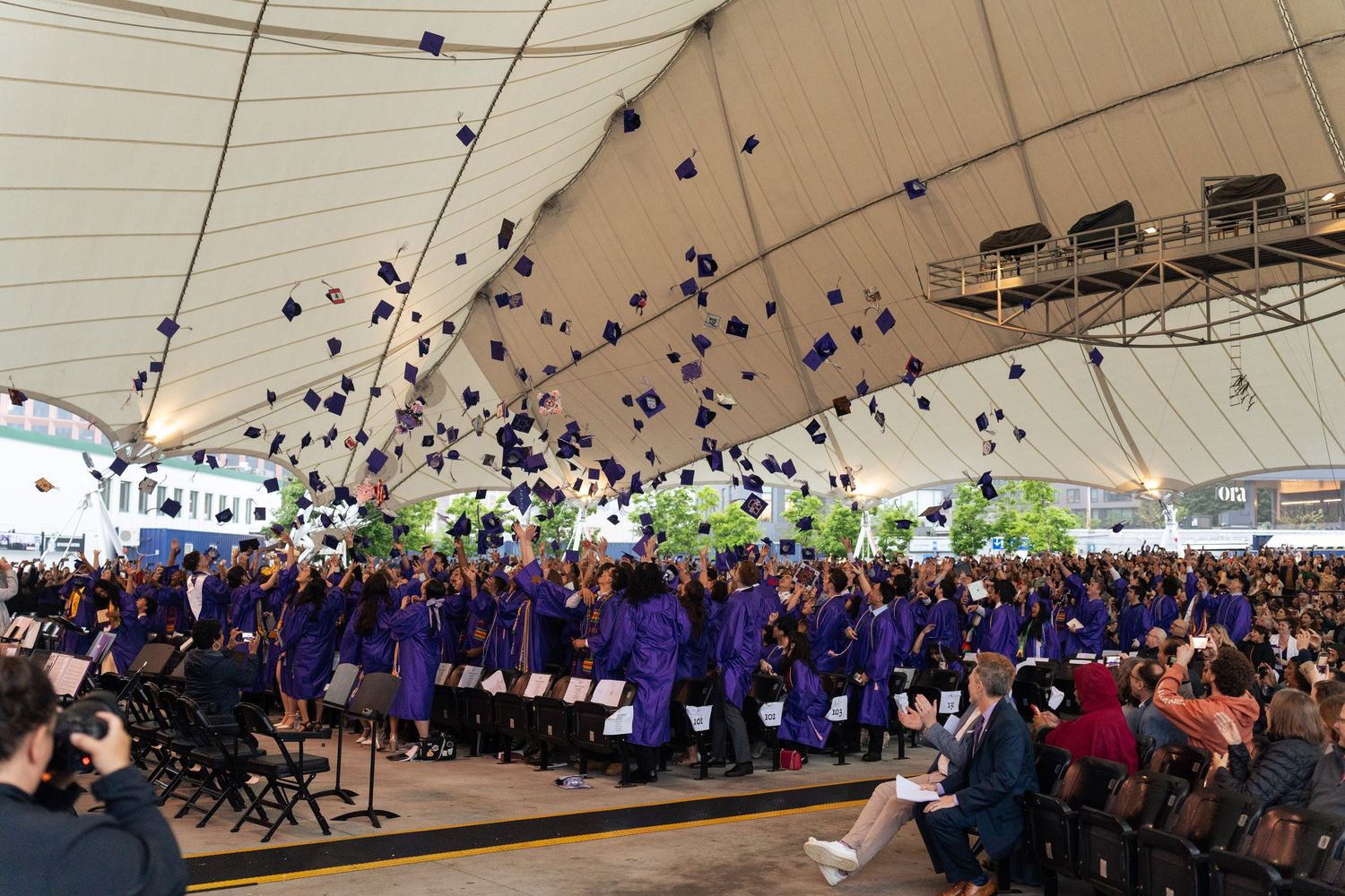 Boston Latin School graduates throw their caps in the air in celebration.