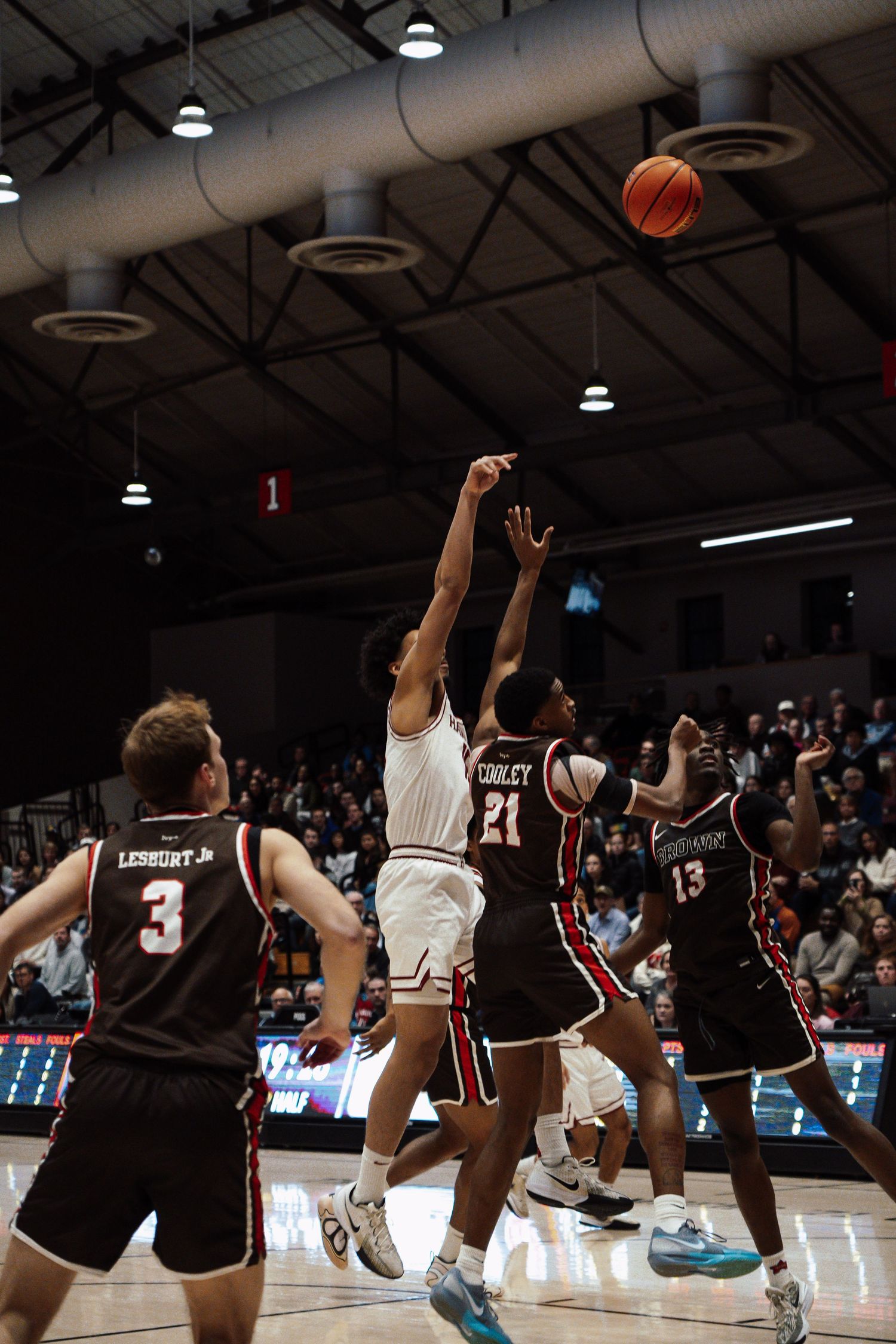 A basketball player shoots a three-pointer over his opponents.
