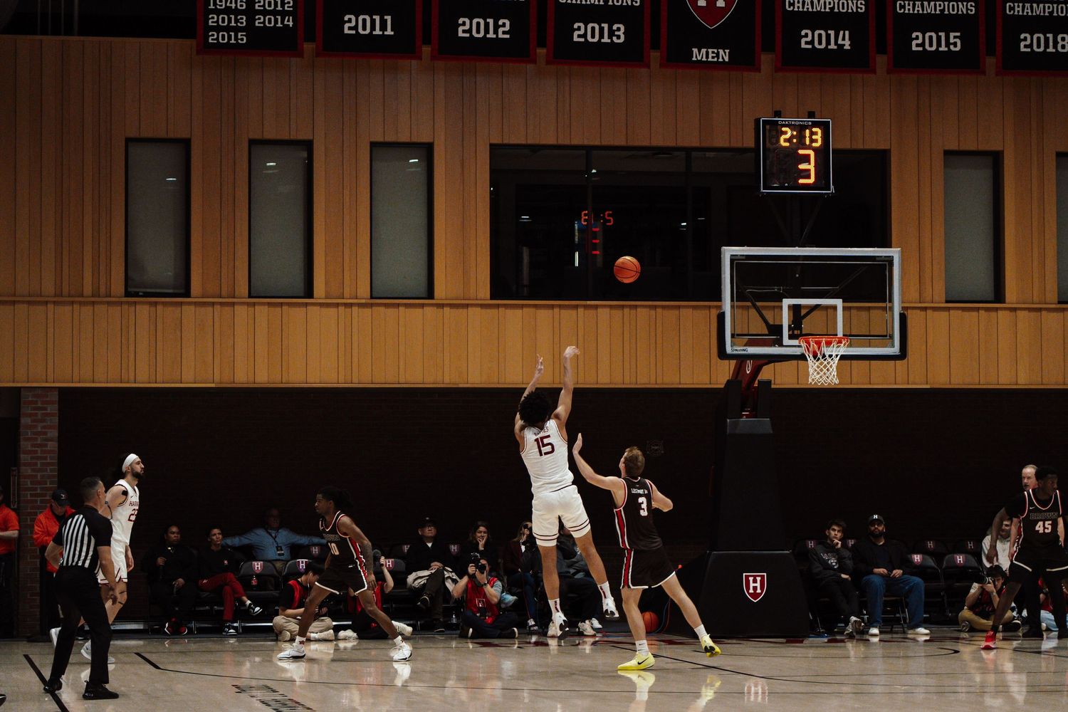 A basketball player shoots a three pointer against his opponents.