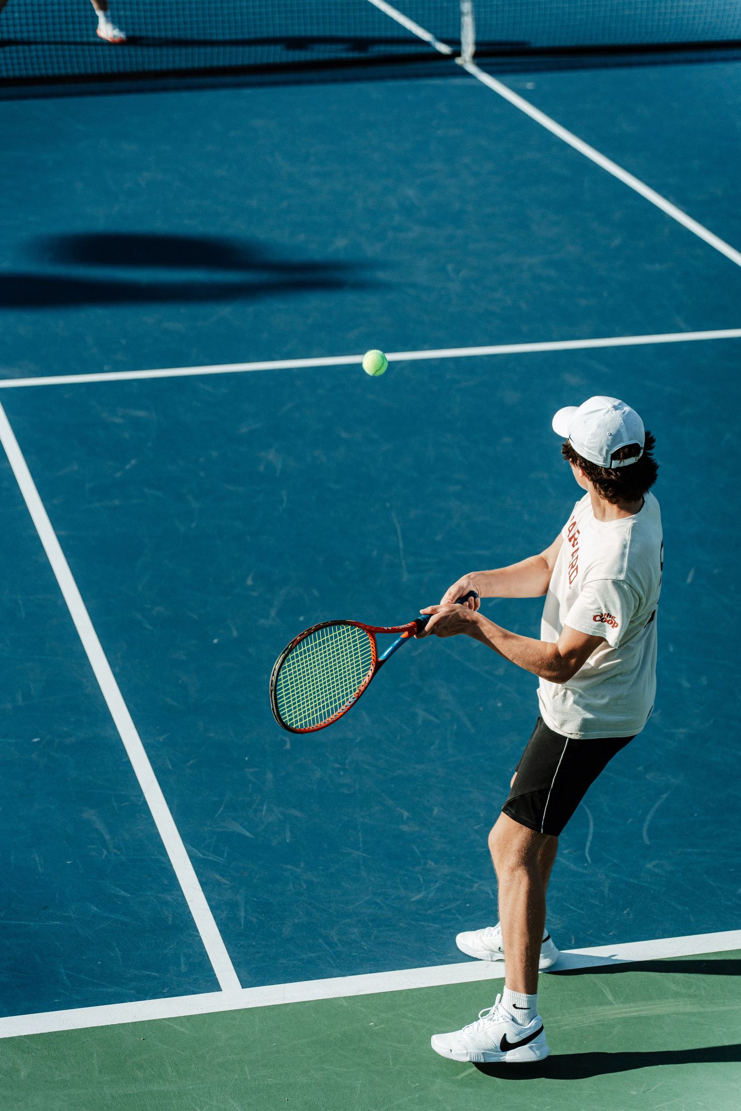 A tennis player returns a serve with an overhand hit.