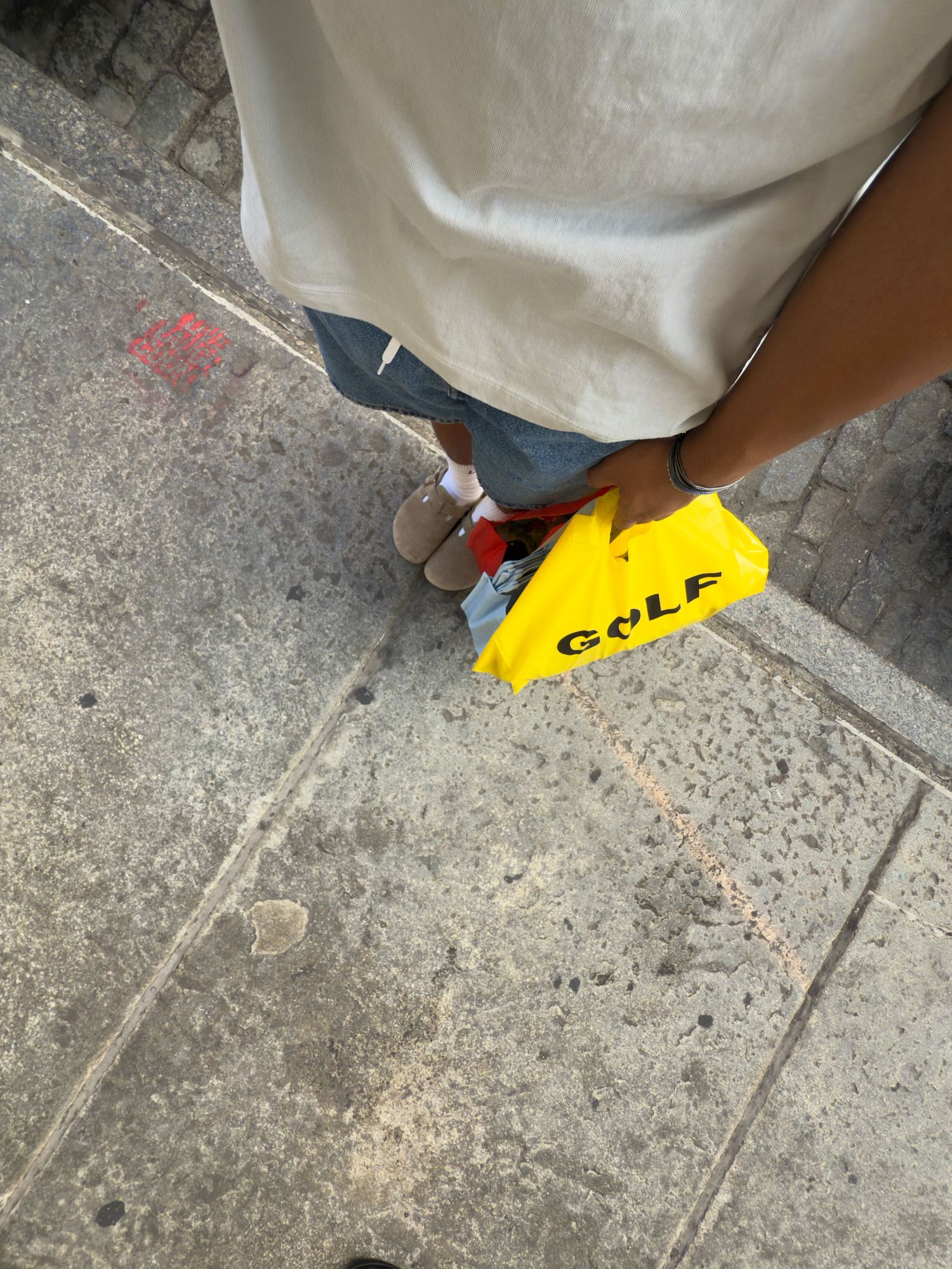 A boy poses with a yellow Golf Wang bag on a SoHo street.