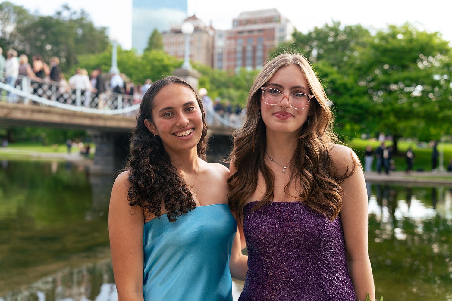 Two girls pose in front of the Swan Pond and bridge at Boston Public Garden