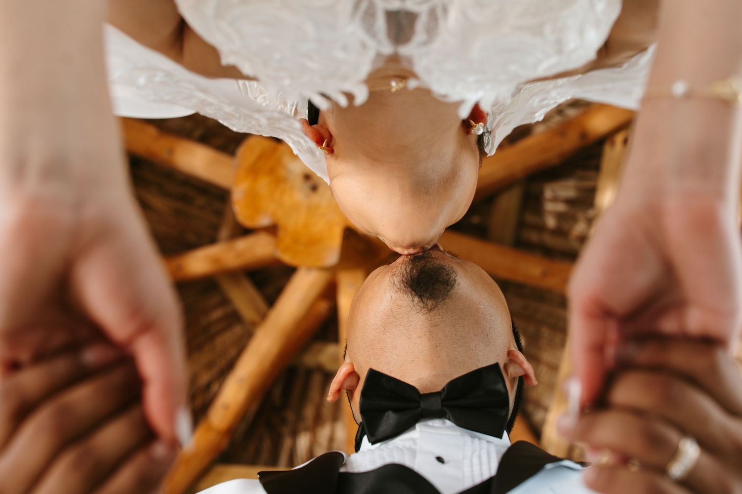 Bride and groom sharing a romantic upside-down kiss at their wedding ceremony, captured from above.