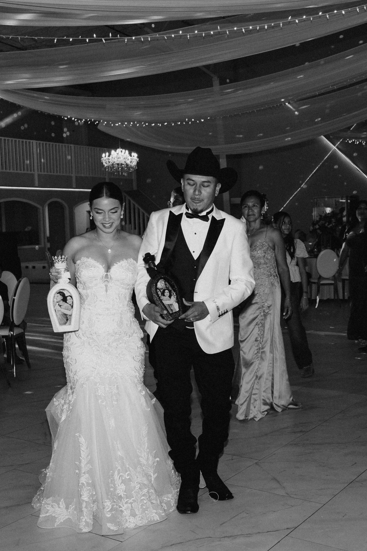 Black and white photo of bride and groom entering wedding reception hall.