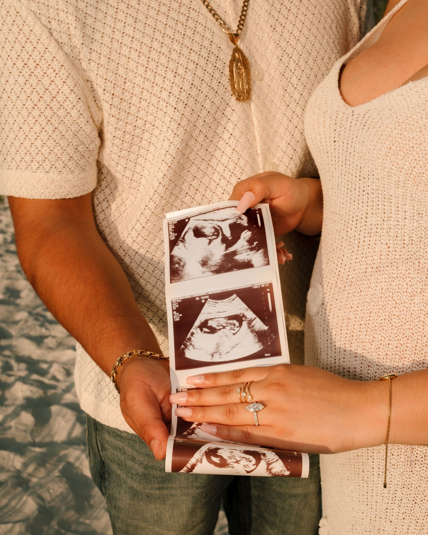 Couple holding ultrasound photos during pregnancy announcement photoshoot outdoors.