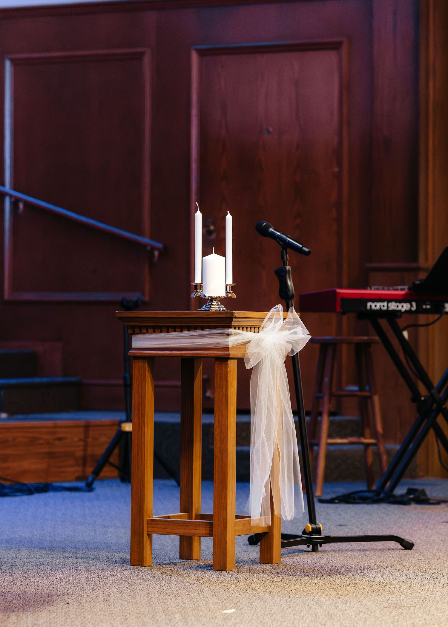 Unity candle table with white bow decoration inside church ceremony venue.