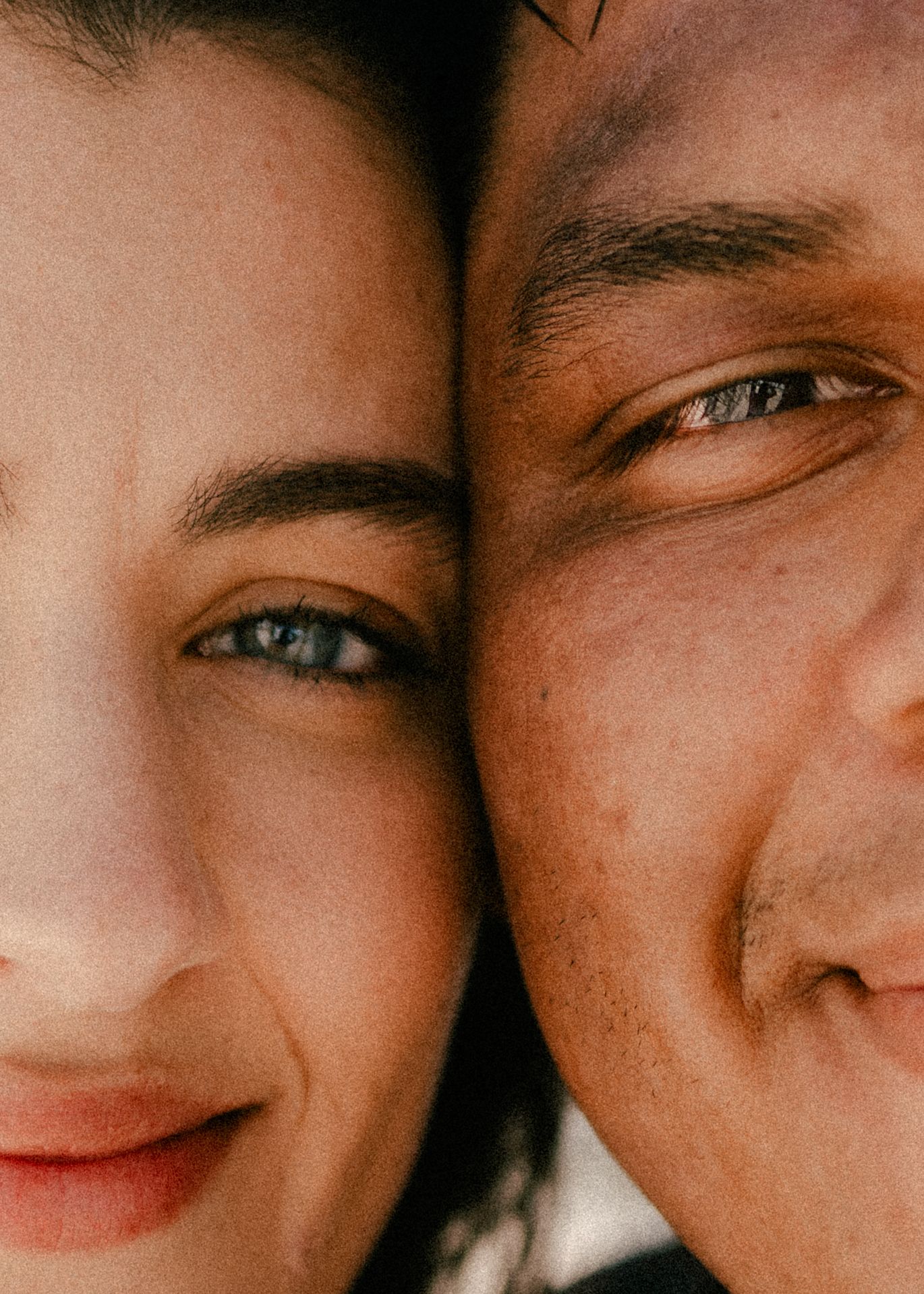 Close-up portrait of two people with faces together, woman with blue eyes and man smiling warmly.