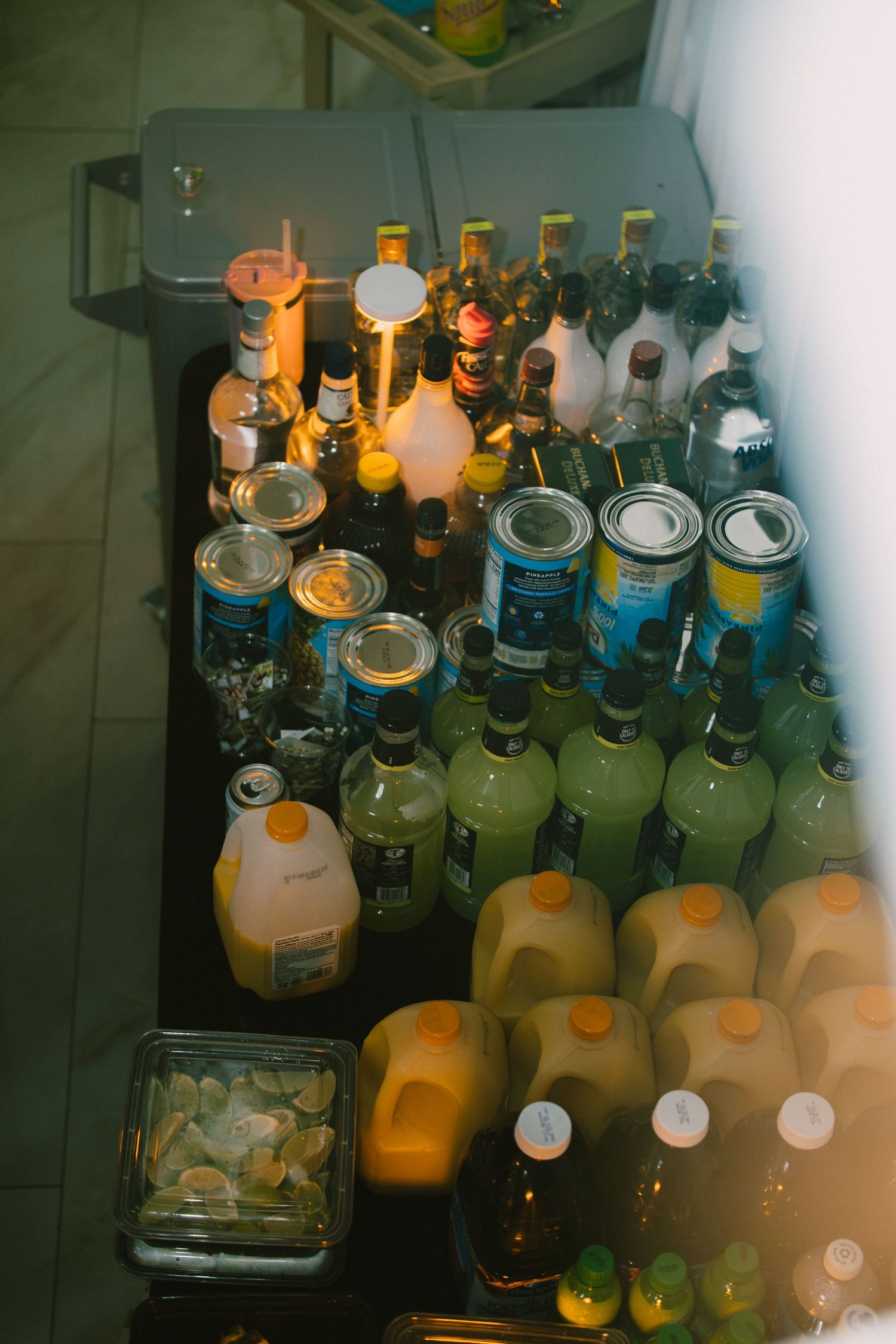 Wedding bar cart stocked with liquor bottles and juice containers for reception.