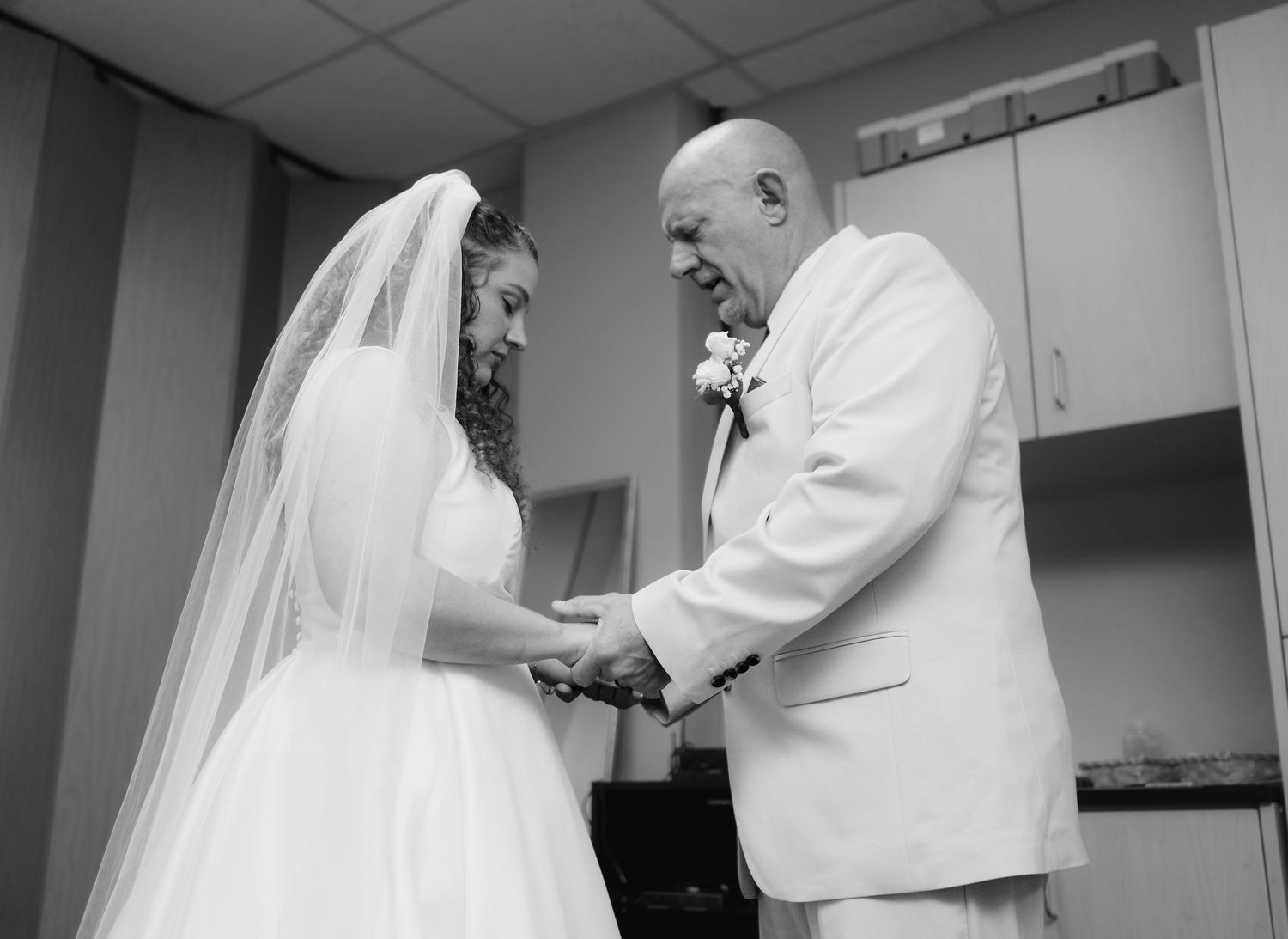 Bride and groom holding hands in black and white pre-ceremony moment.