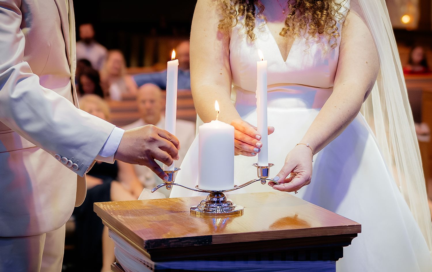 Bride and groom lighting unity candles during a wedding ceremony at a church altar.