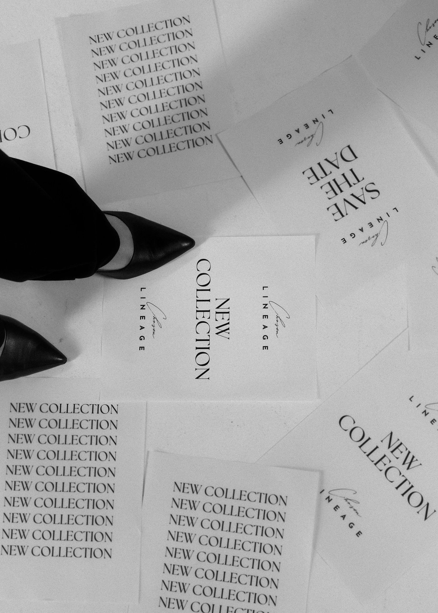 Black and white flat lay of New Collection and Save the Date cards with a stylish shoe stepping on them.