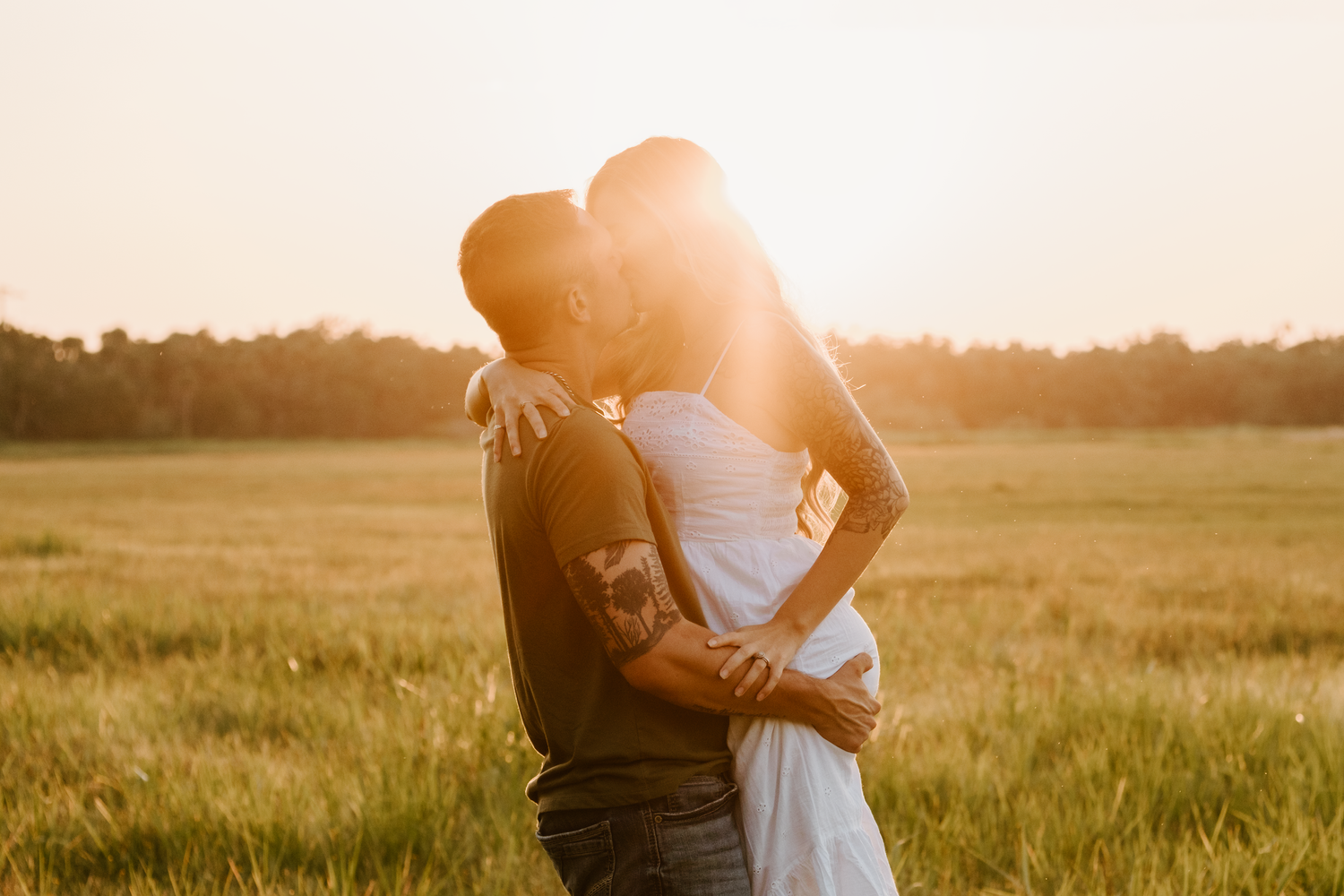 A romantic golden hour embrace in a sunlit meadow with tall grass at sunset.