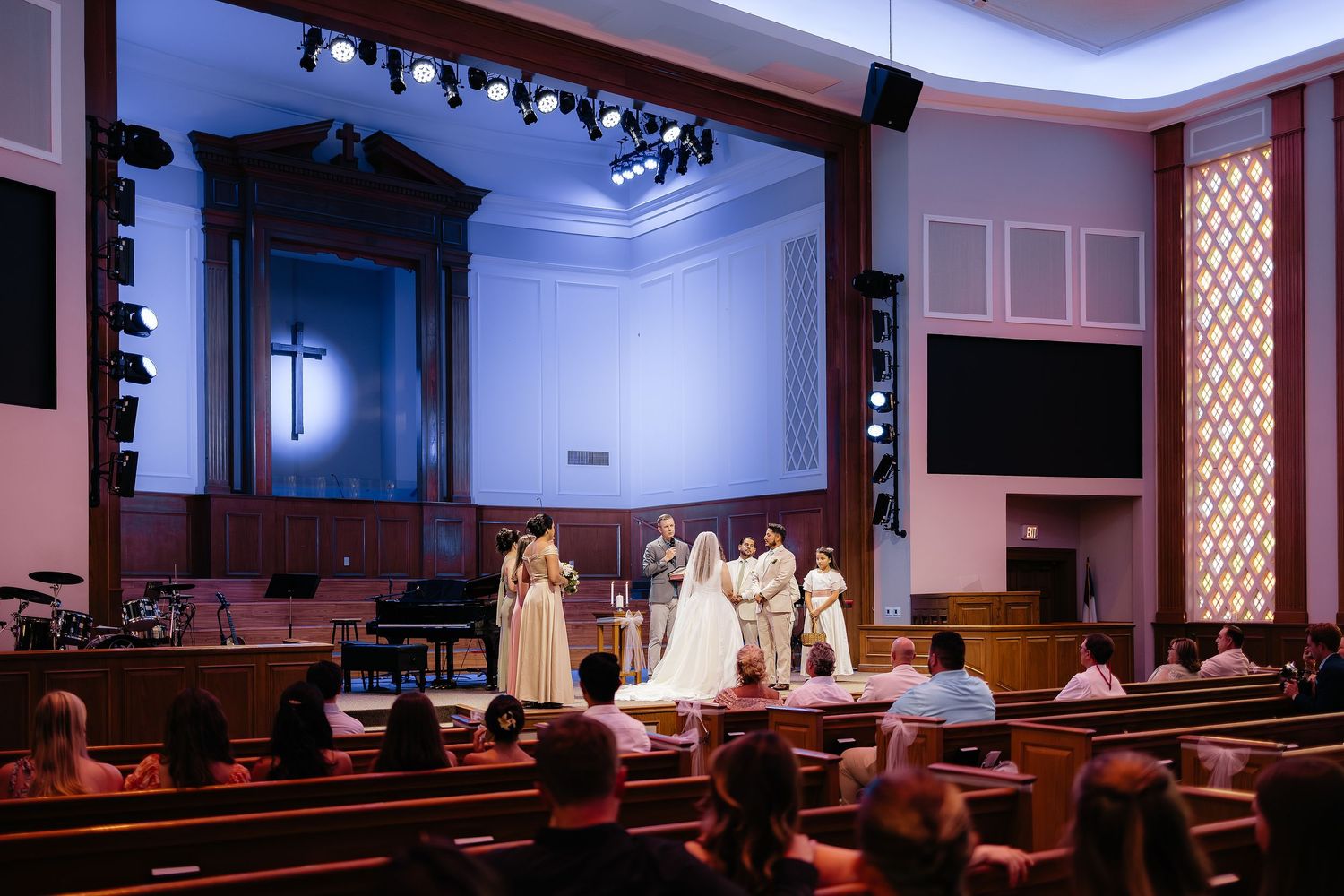Wedding ceremony at church altar with bridal party and guests in pews.