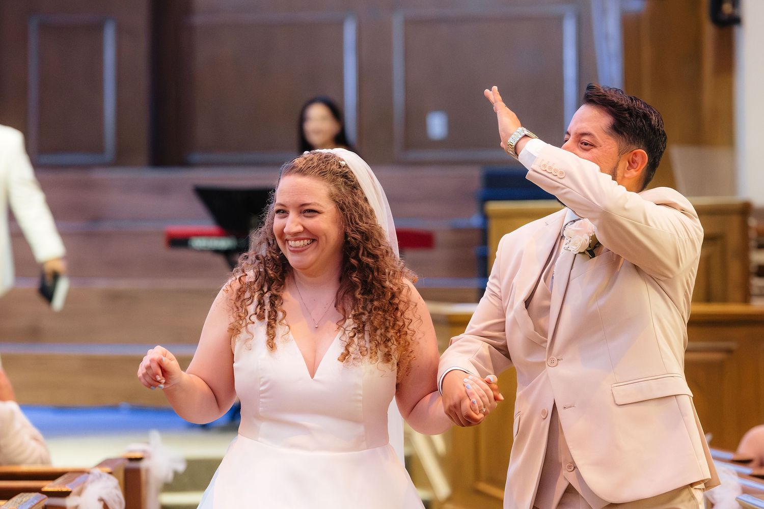 Joyful newlyweds holding hands and celebrating after their wedding ceremony inside a church.