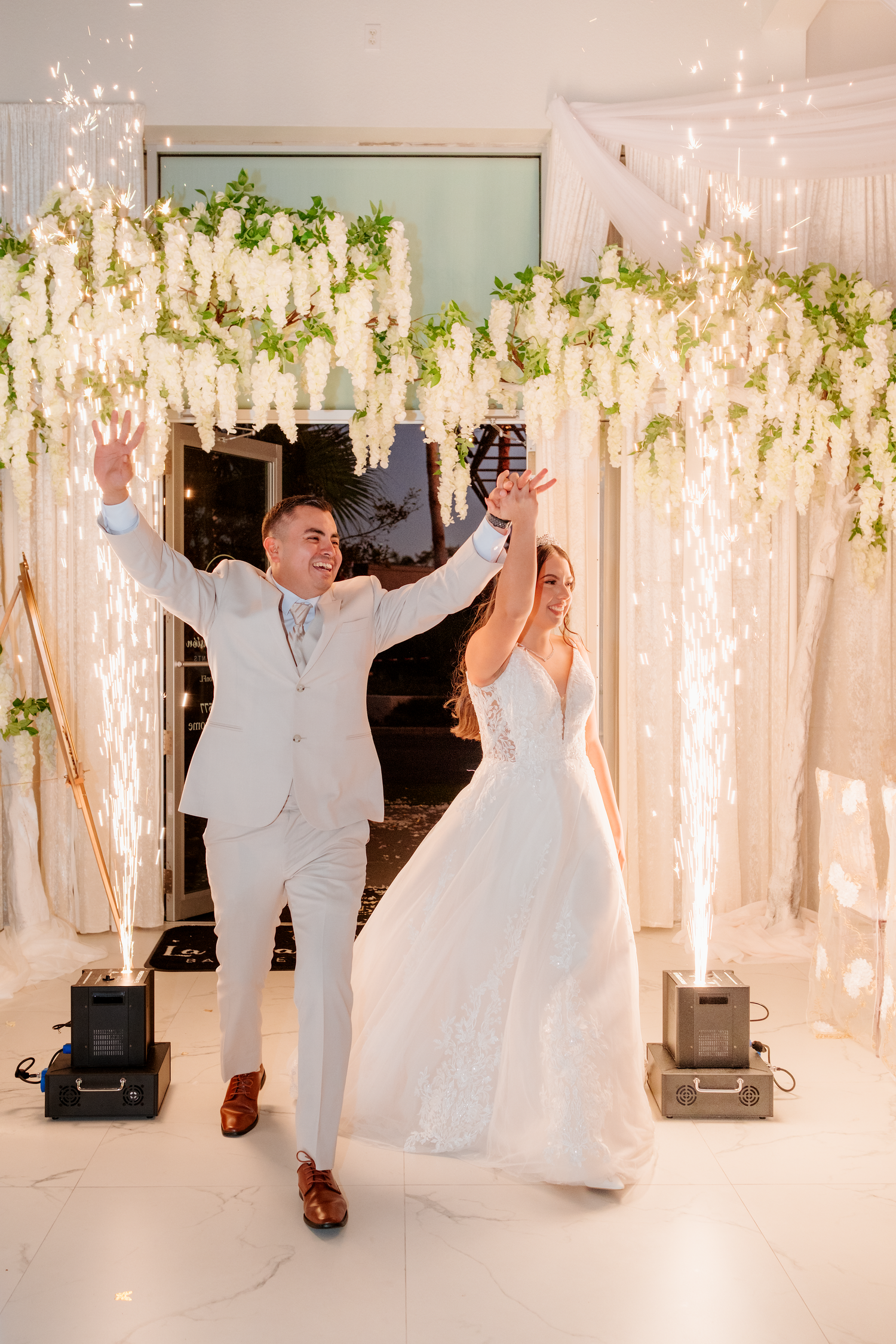 Bride and groom celebrate grand entrance with sparkling cold sparklers at wedding reception.
