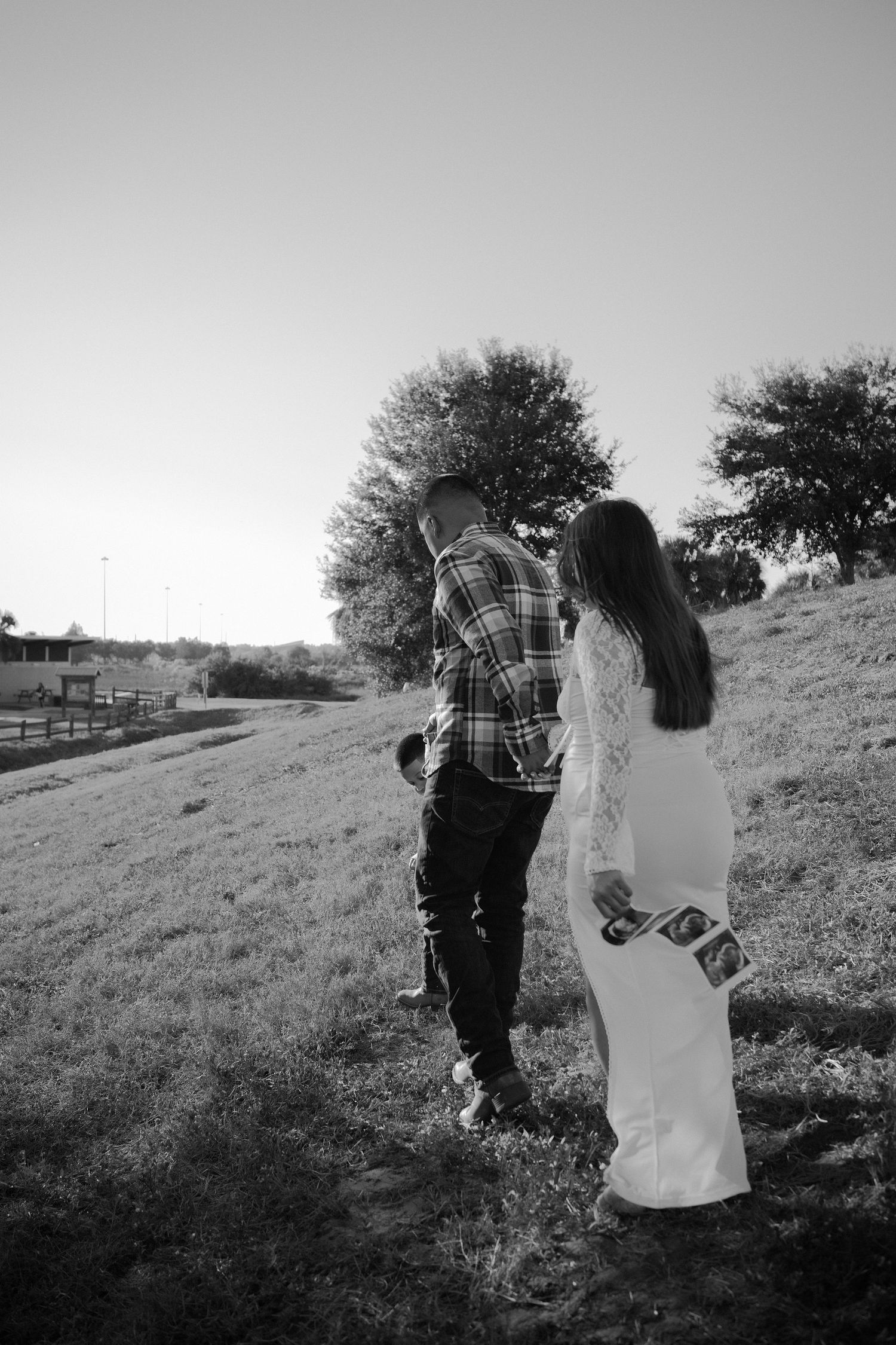 A couple embraces and dances together on a grassy hillside in a series of black and white photographs.