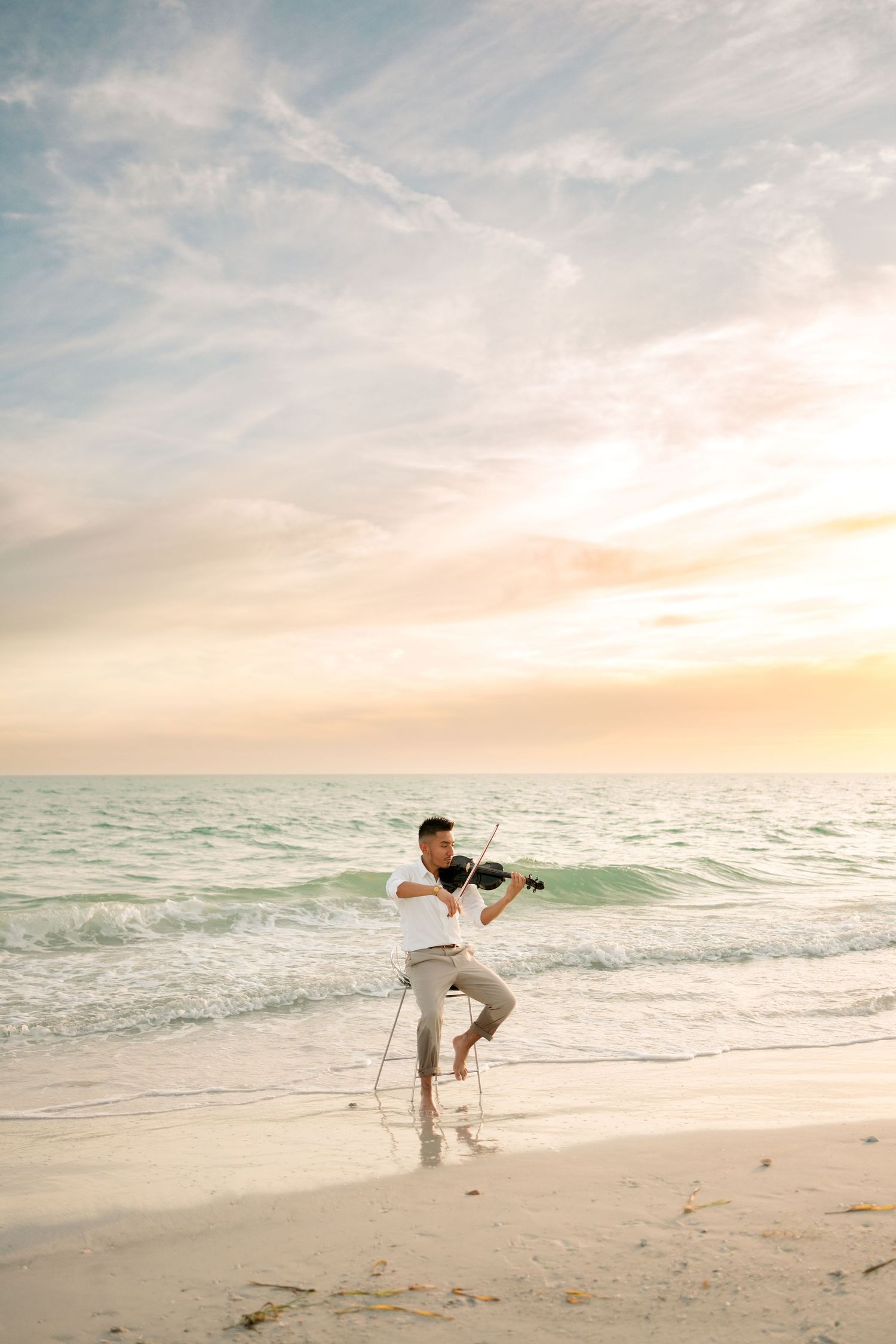 A couple dances and embraces on a serene beach at sunset, creating romantic silhouettes against the ocean backdrop.