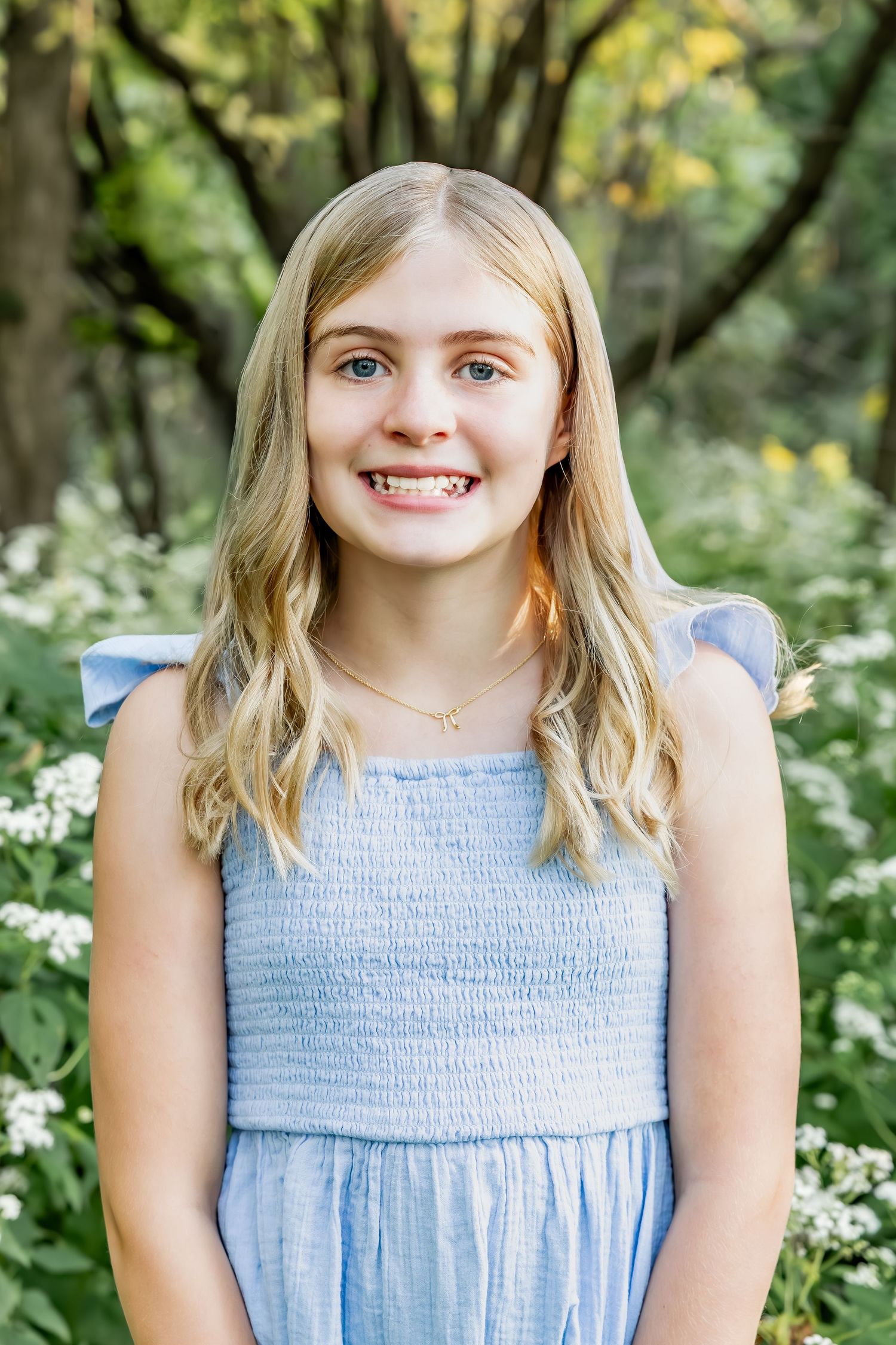Portrait sequence in light blue dress against garden background with white flowers.
