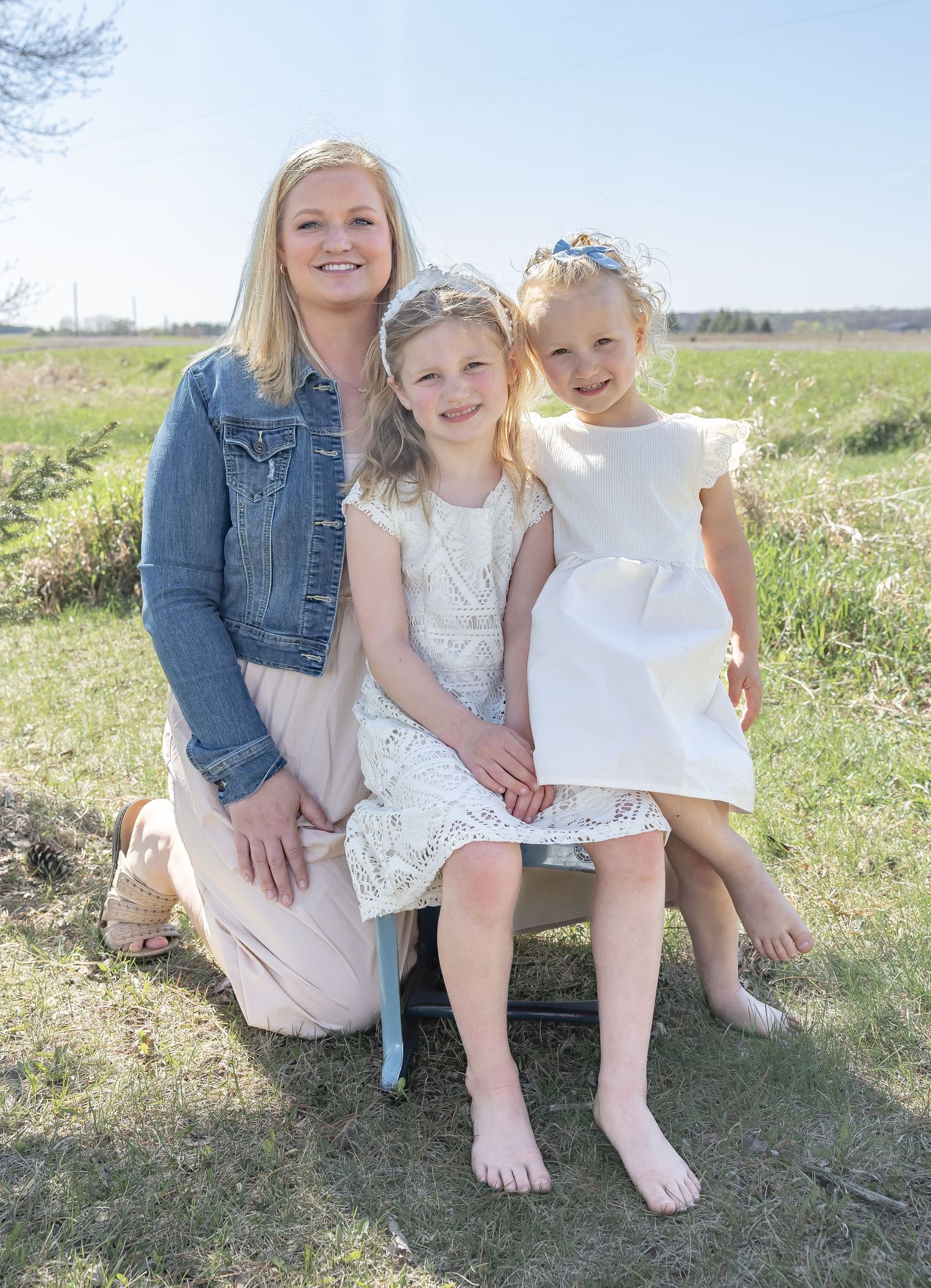 Sunny outdoor family portrait in a wildflower field wearing white dresses.