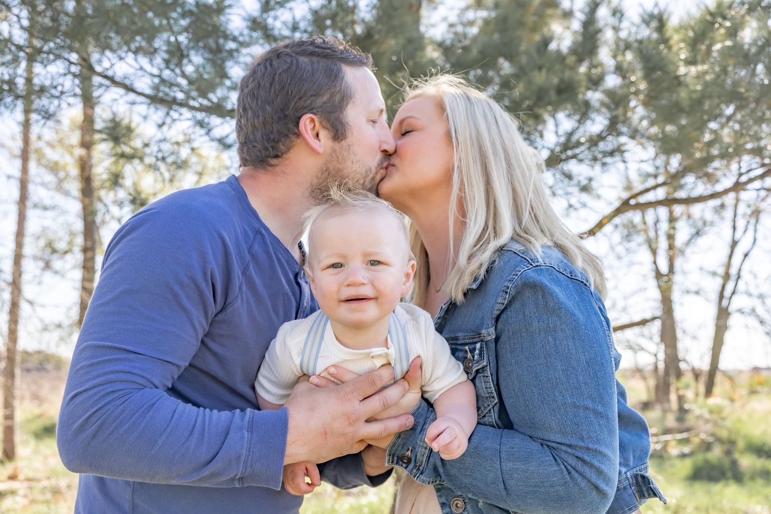 Tender family moments captured in golden sunlight with pine trees in background.