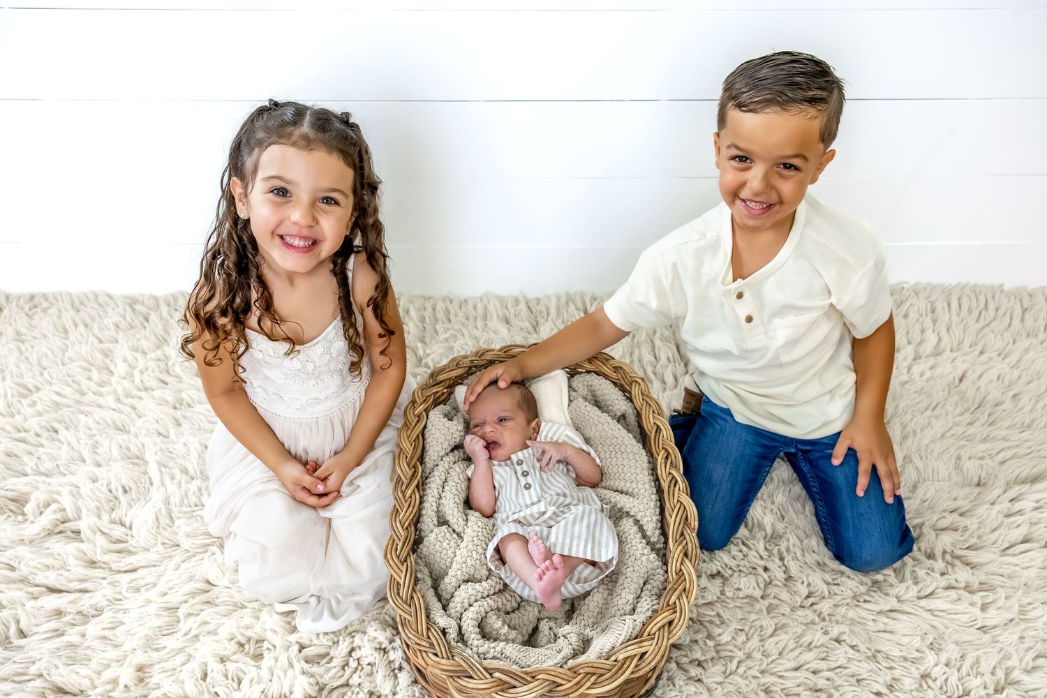 Siblings lying on a cream colored shag rug during a lifestyle photo session.