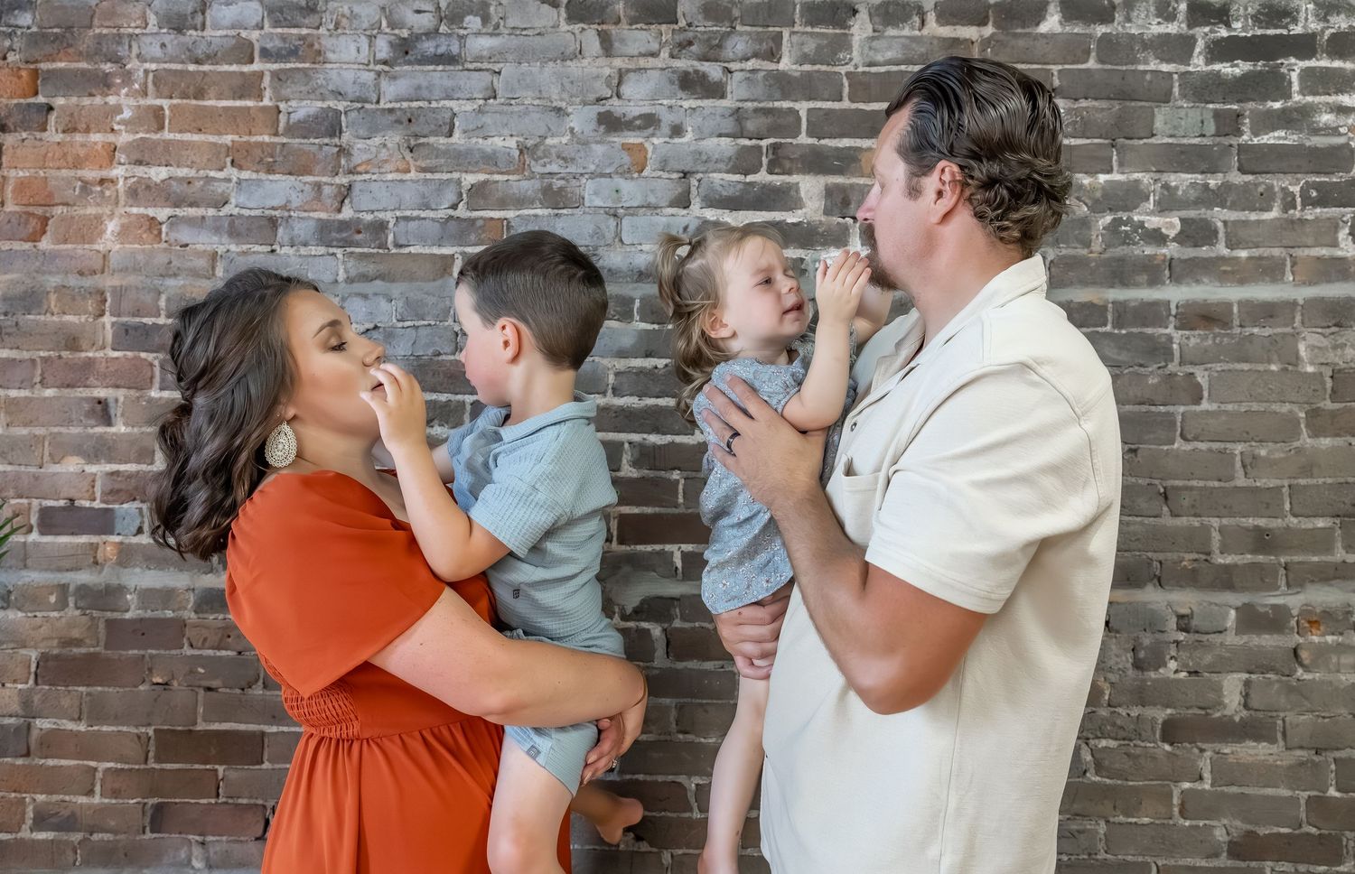 Family enjoying a fun moment together against a rustic brick wall background.