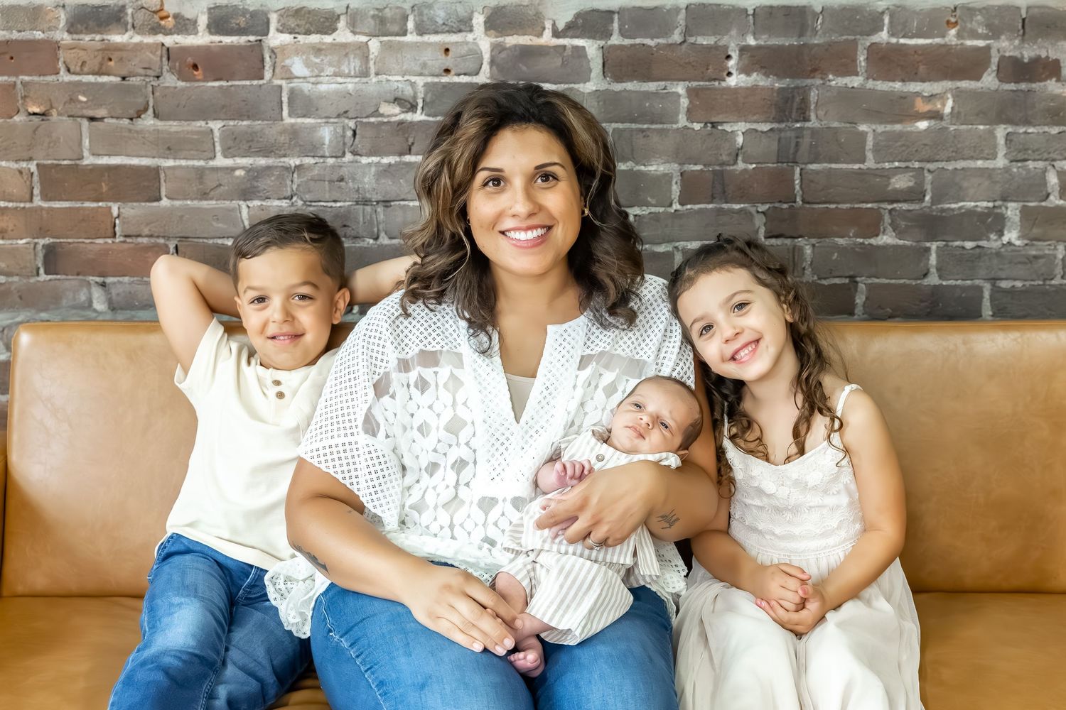 Casual family portrait against rustic brick wall with leather seating.