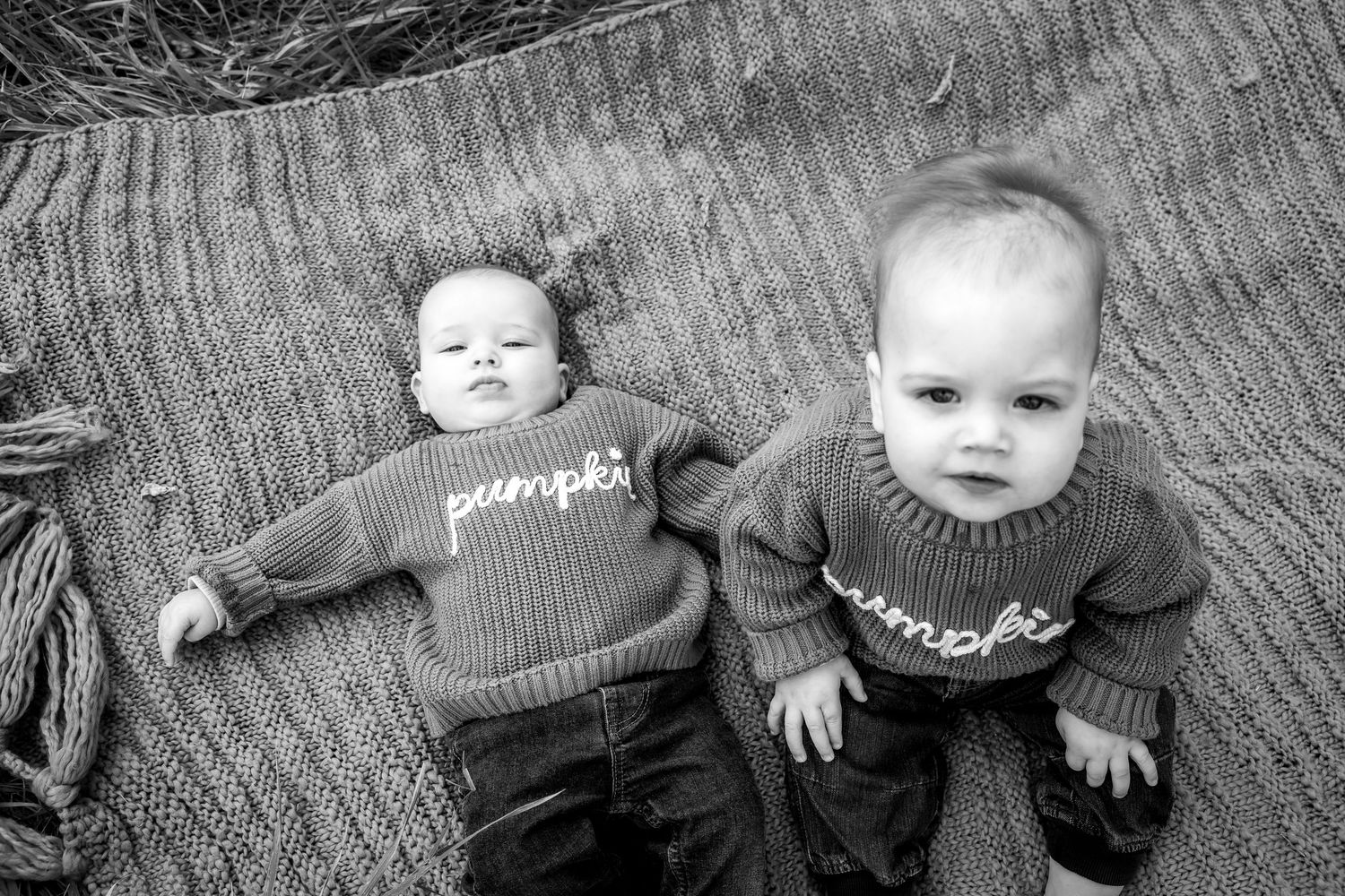 Black and white portrait of two people laying on a textured surface.