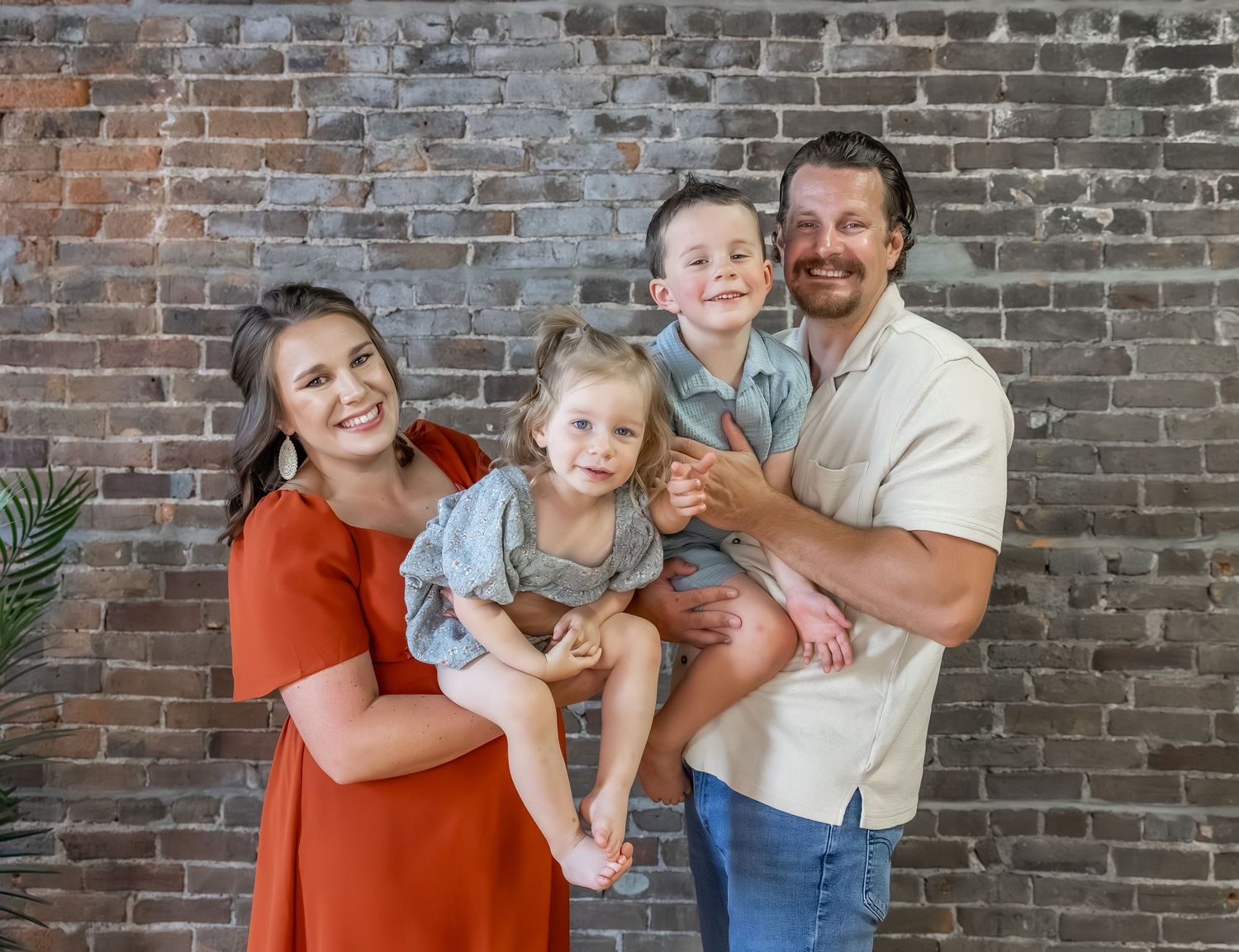 Casual family photoshoot with natural interactions against industrial backdrop.