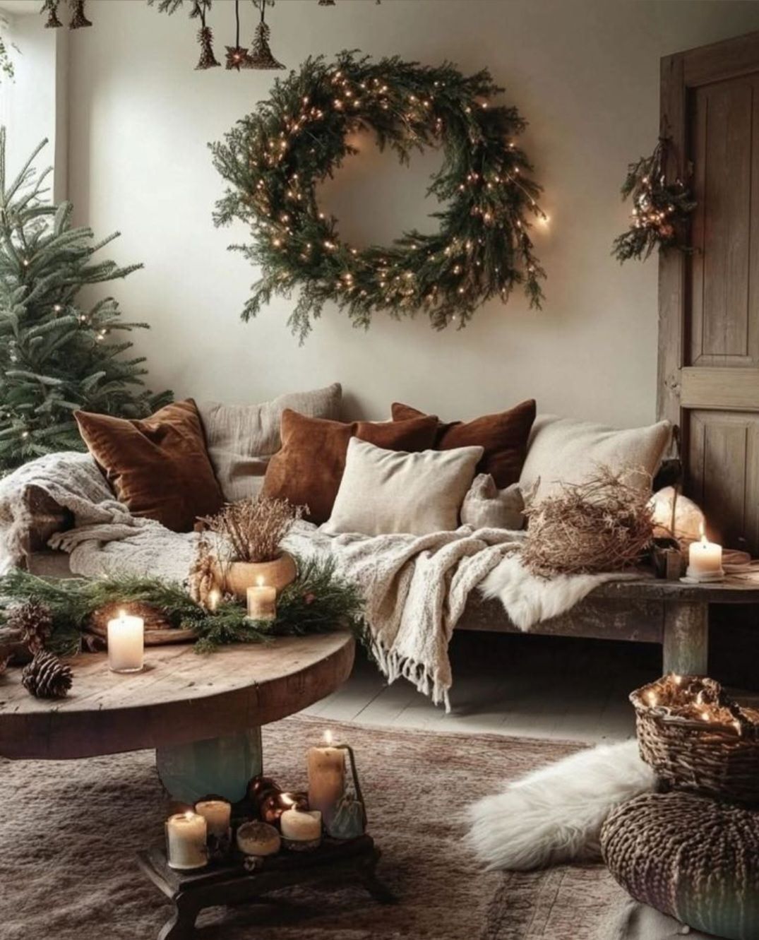 Hygge living room with Christmas wreath, candles, and cozy throw pillows.