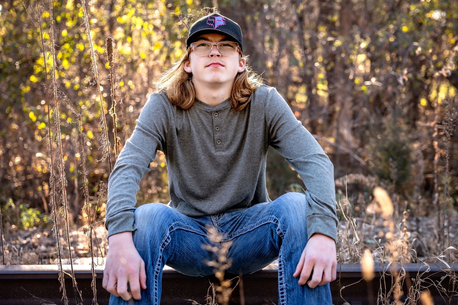 Outdoor portrait series showing relaxed poses on wooden bench with autumn trees in background.