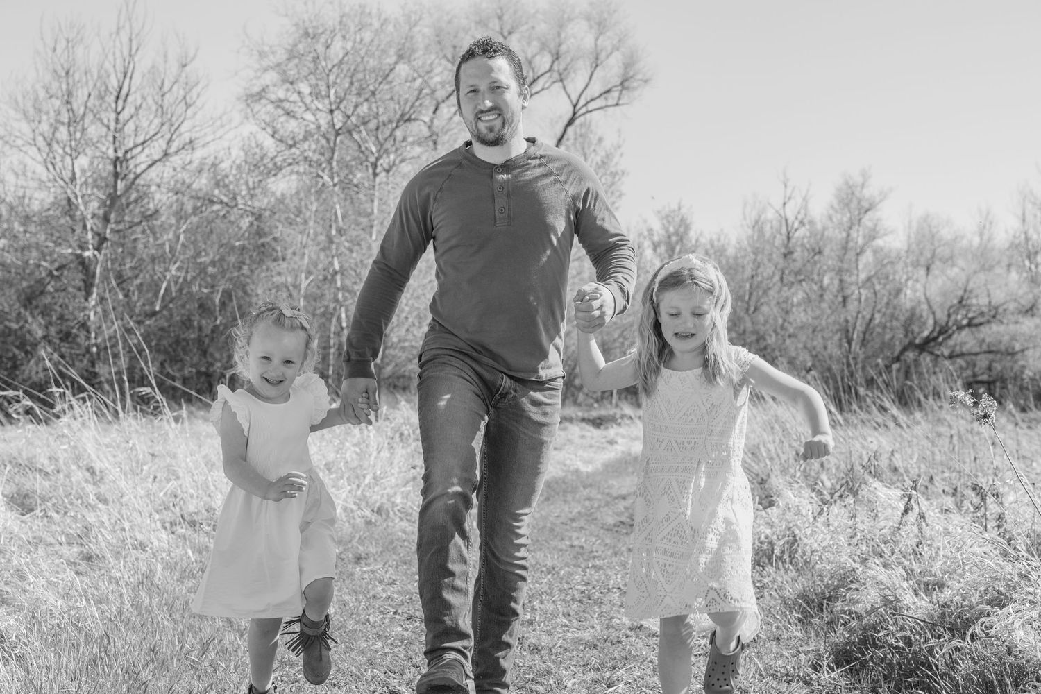 Family enjoying a playful moment together in a natural outdoor setting with trees and grass.