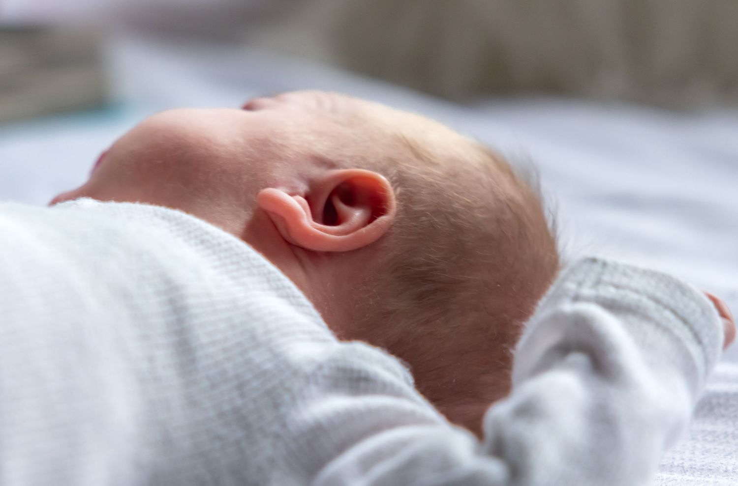 Side profile of sleeping newborn against white background.