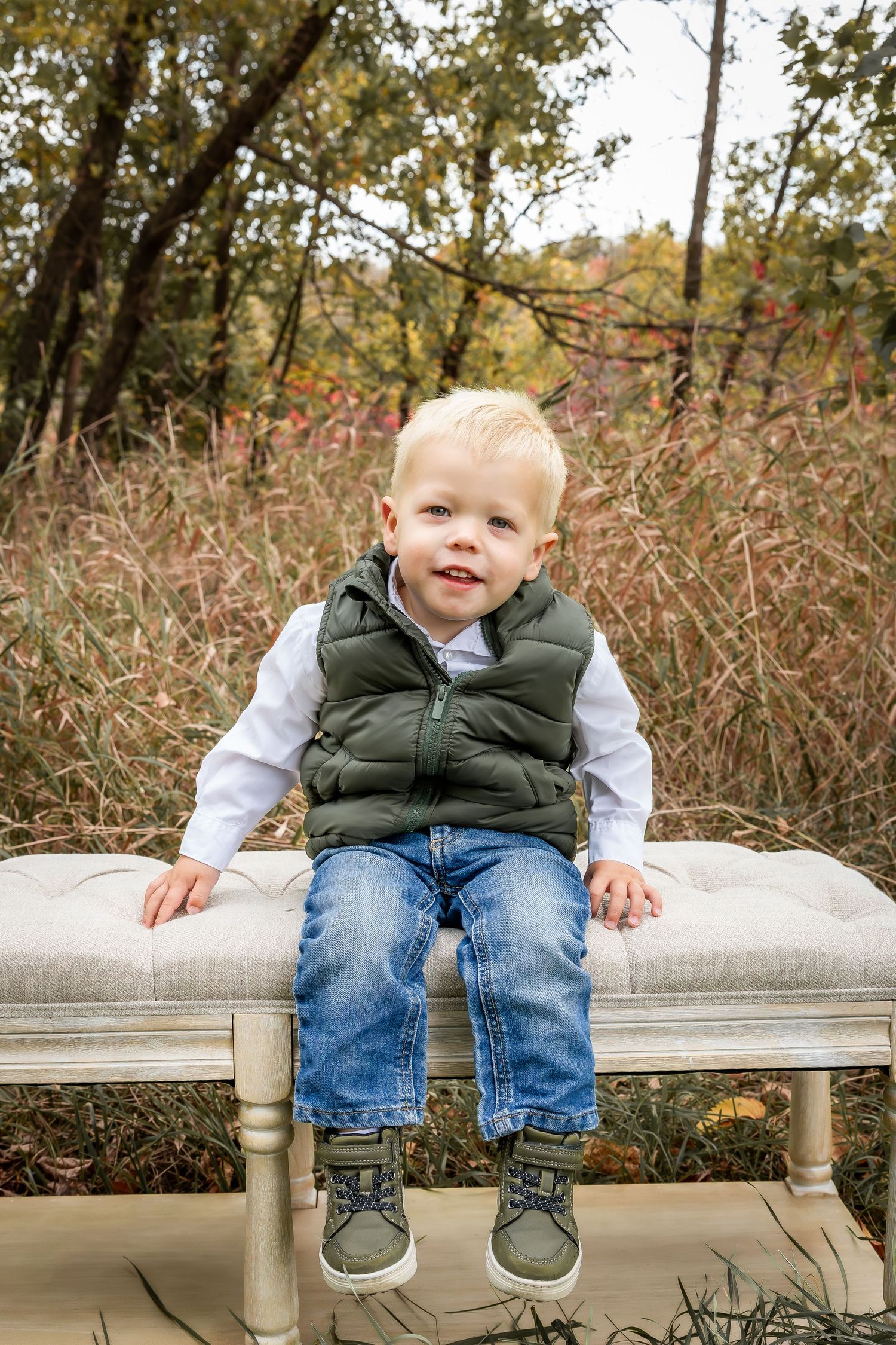 Person sitting on white bench outdoors surrounded by autumn foliage.
