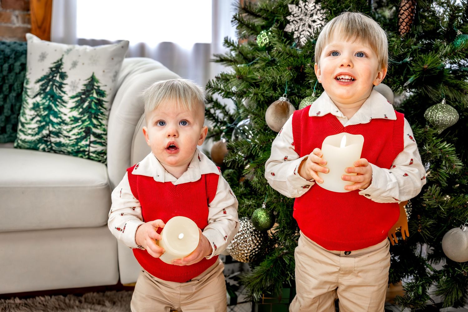 A young child in festive holiday attire poses in front of a decorated Christmas tree.