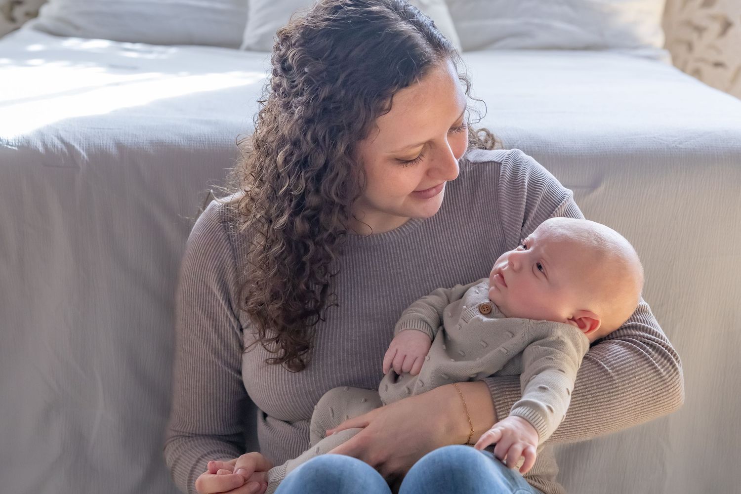 A tender moment between parent and infant while relaxing on a cozy gray couch.